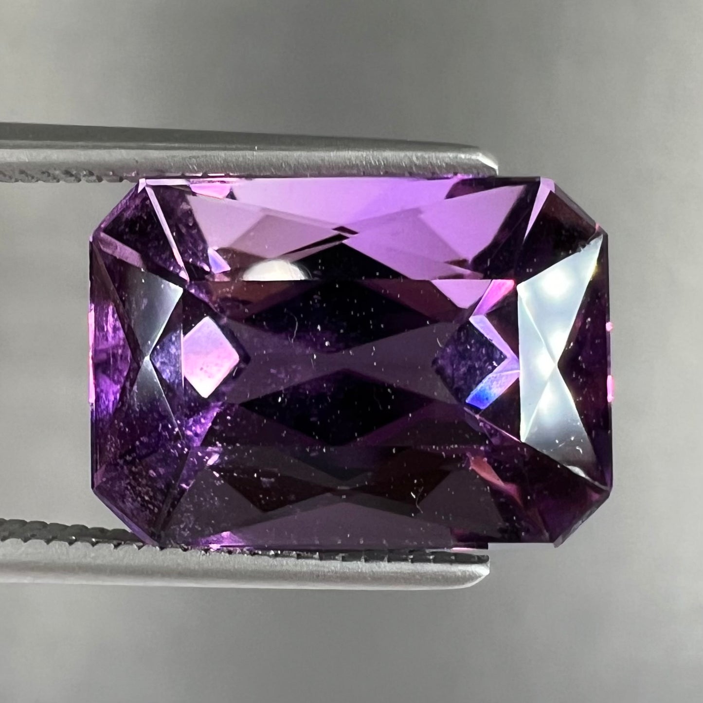 A loose, modified radiant cut amethyst stone.