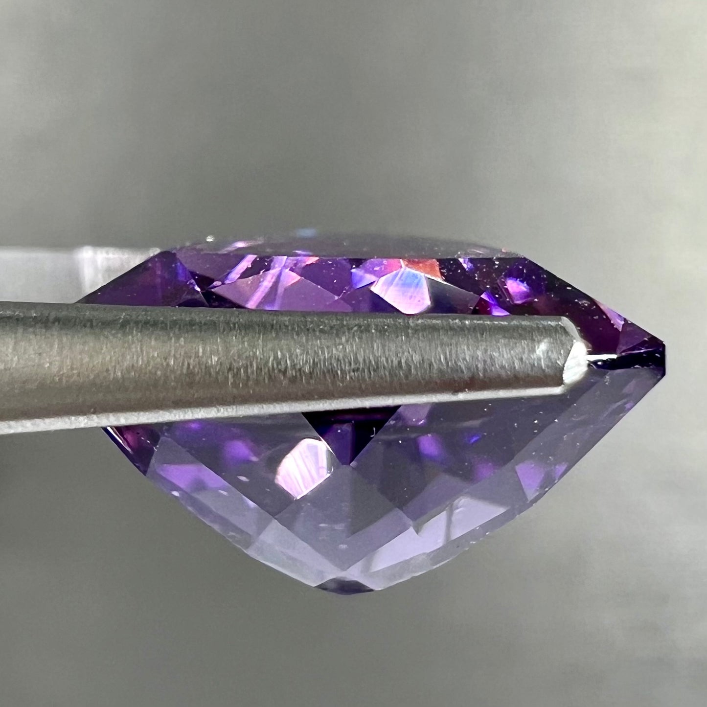 A loose, faceted trillion cut amethyst gemstone.