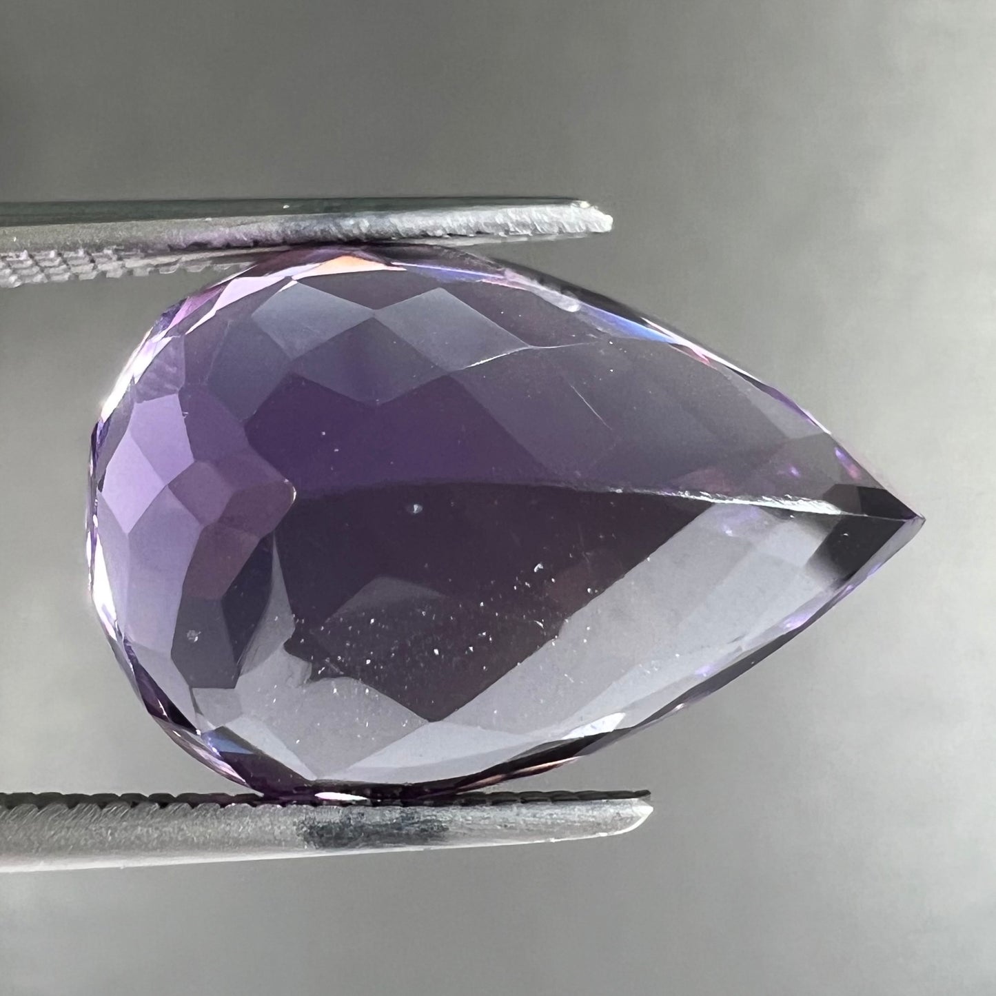 A loose, pear shaped amethyst gemstone. The stone is a medium purple color.