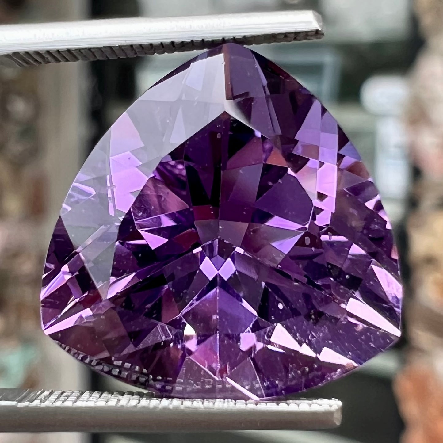 A loose, faceted trillion cut amethyst gemstone.