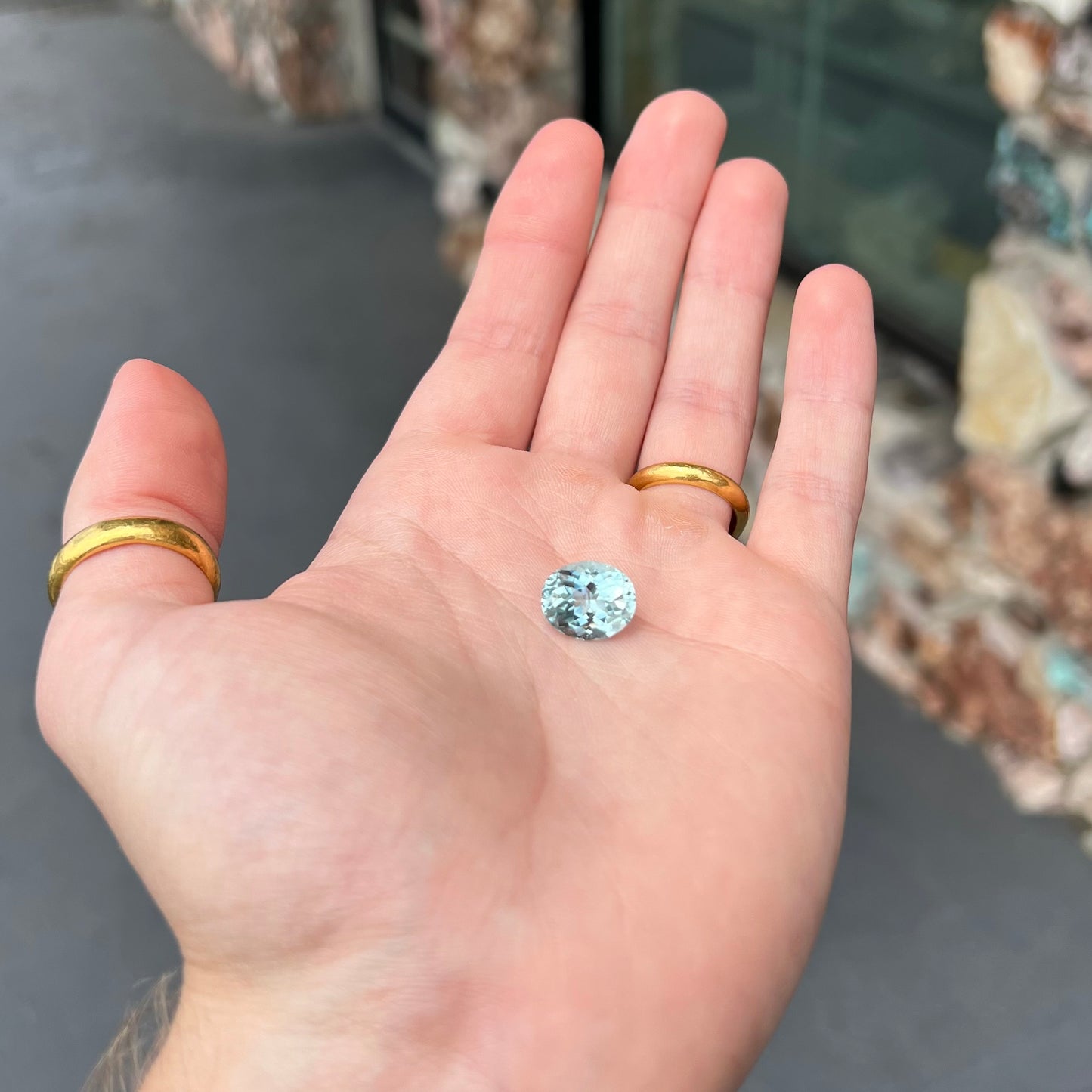 A loose, faceted oval cut aquamarine gemstone from Brazil. The stone is greenish blue color.