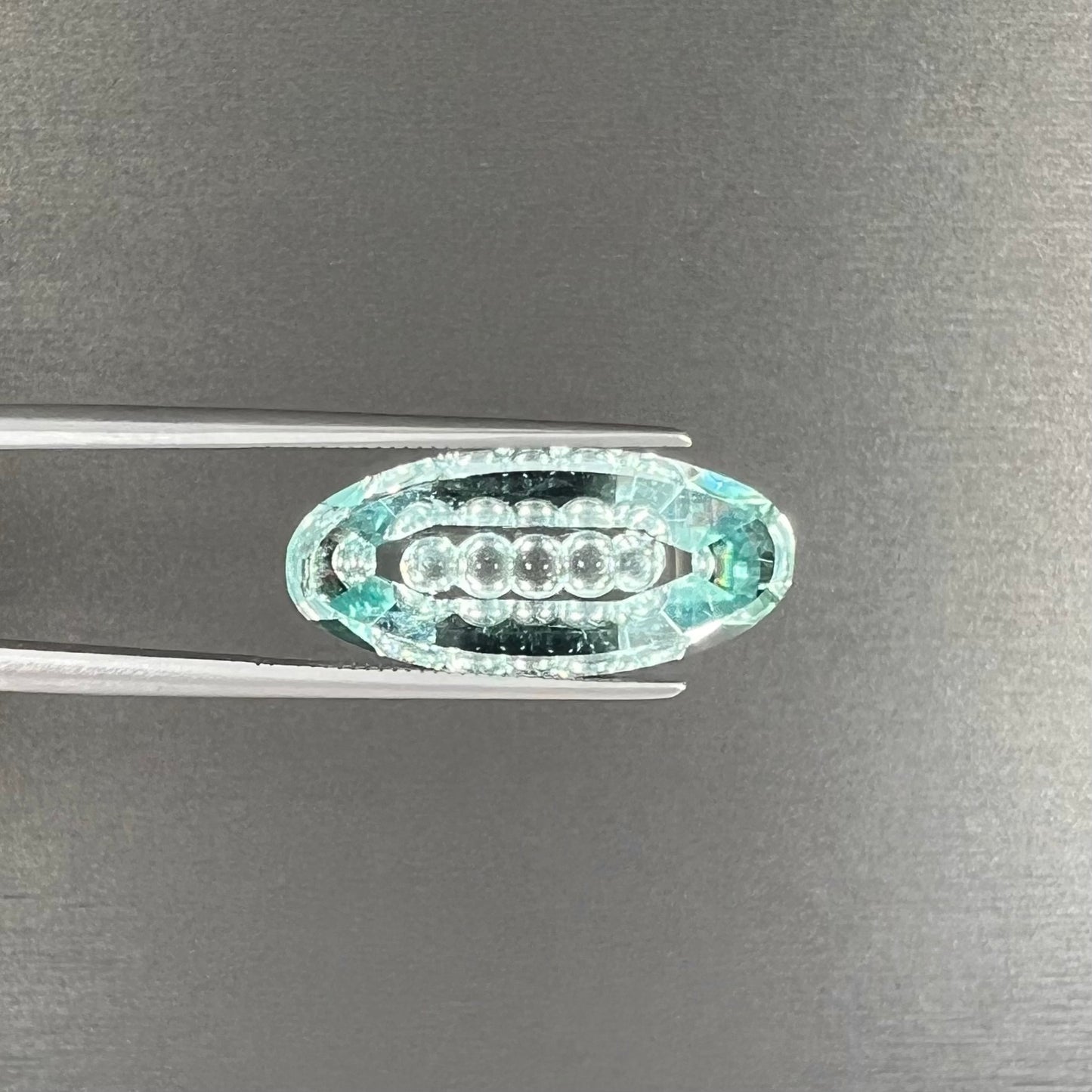 An oval fantasy cut greenish blue aquamarine stone cut by gem carver, Arthur Lee Anderson.