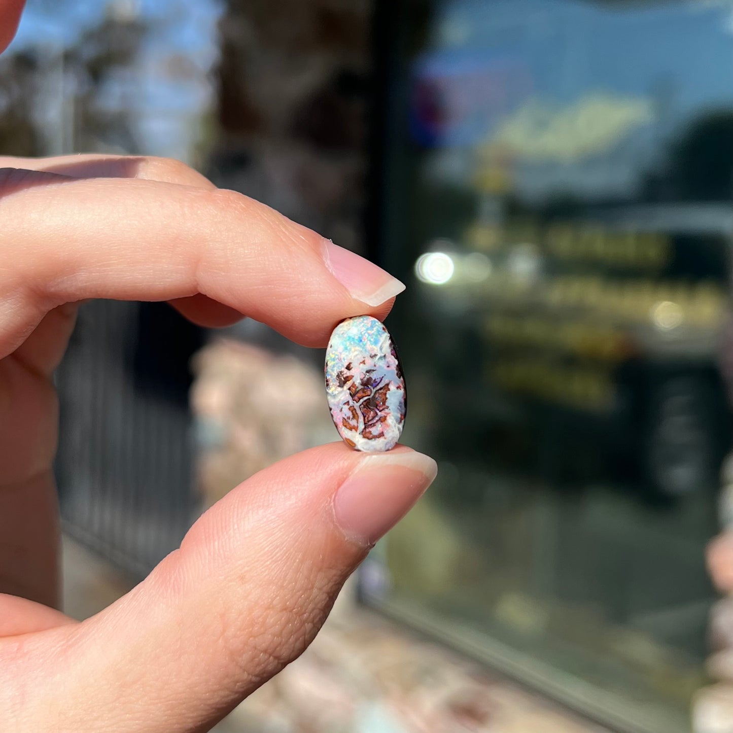An oval cabochon cut boulder opal stone from Koroit, Australia. The opal has a white body tone.