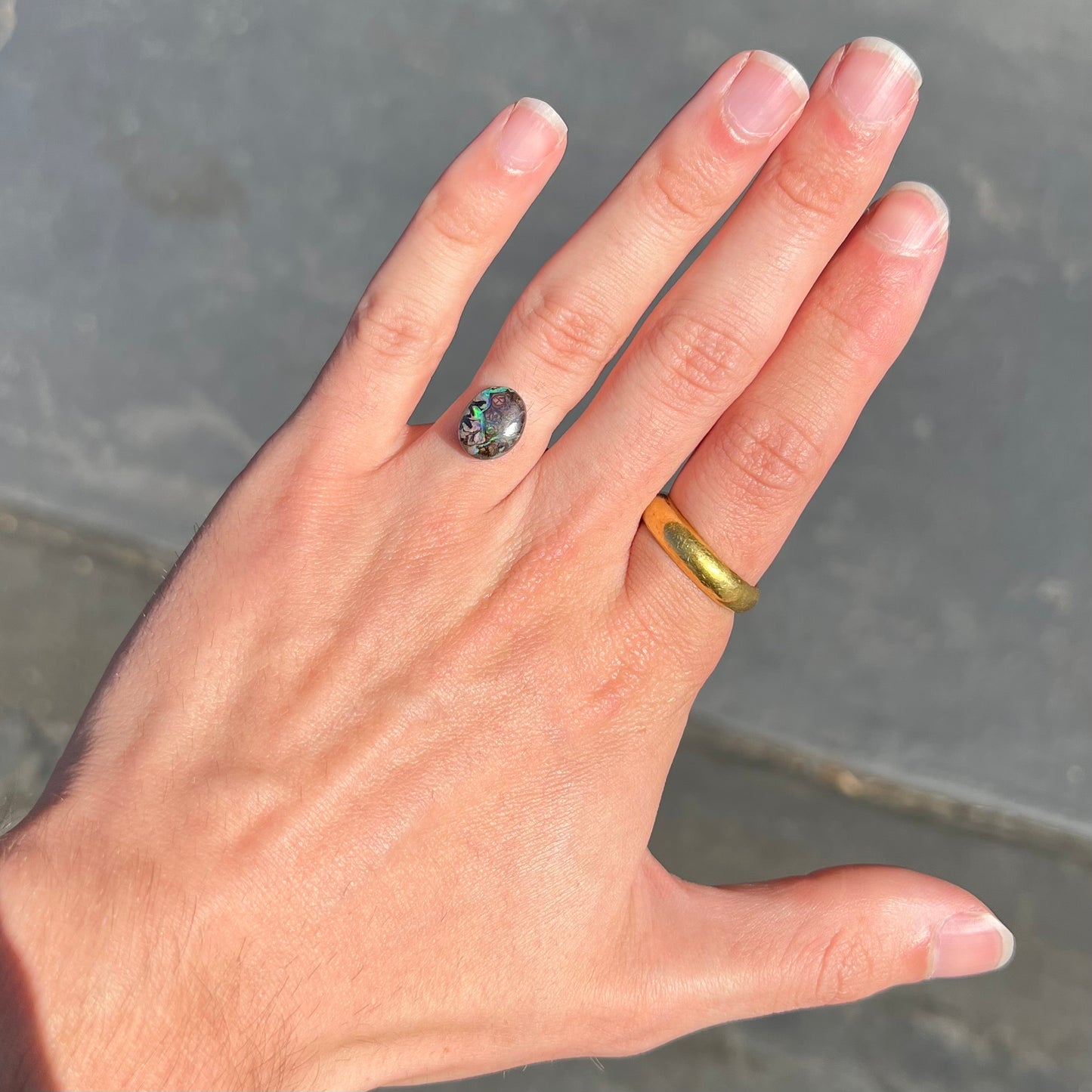 A loose, oval cabochon cut boulder opal stone from Koroit, Australia. The opal has a bright green flash.