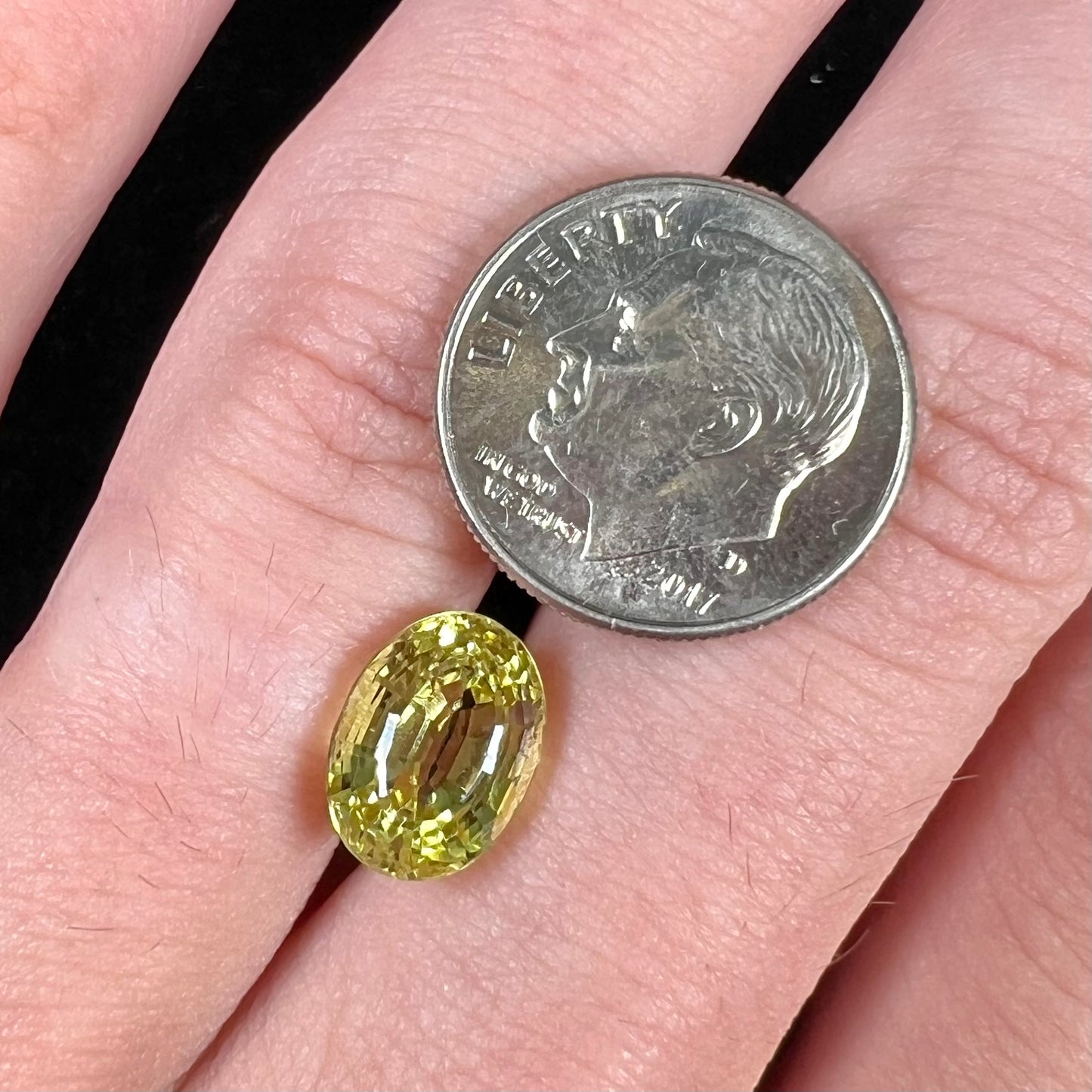 A loose, oval cut greenish yellow chrysoberyl stone.