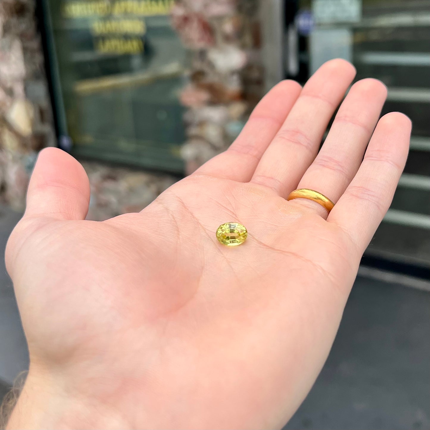 A loose, oval cut greenish yellow chrysoberyl stone.