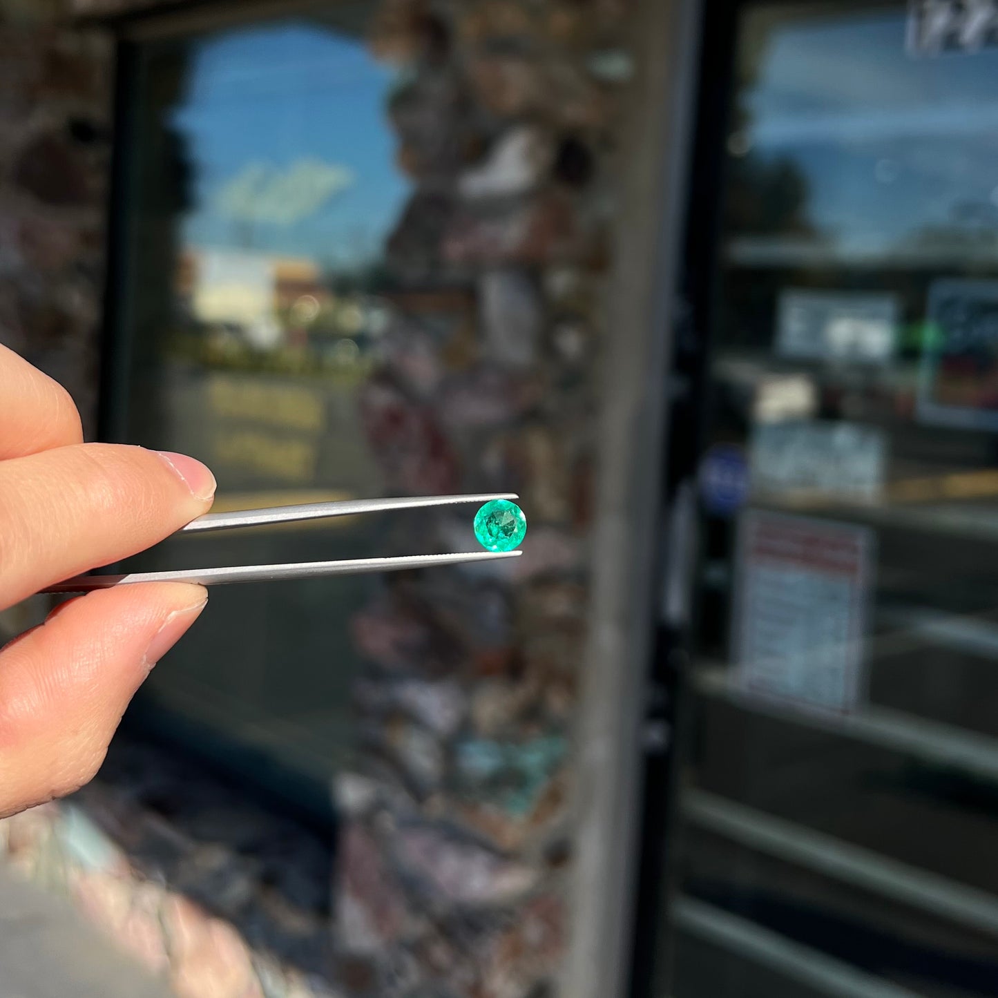 A loose, round brilliant cut natural emerald stone.