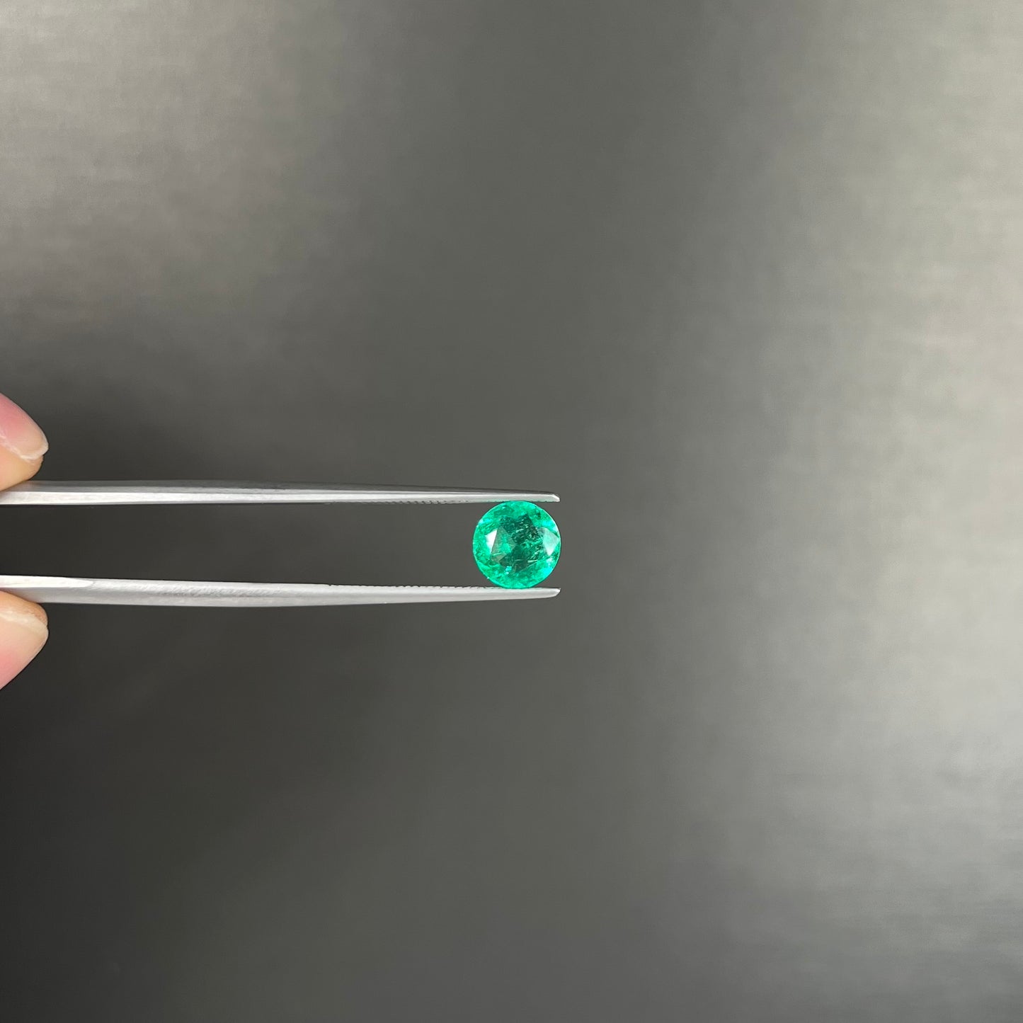 A loose, round brilliant cut natural emerald stone.
