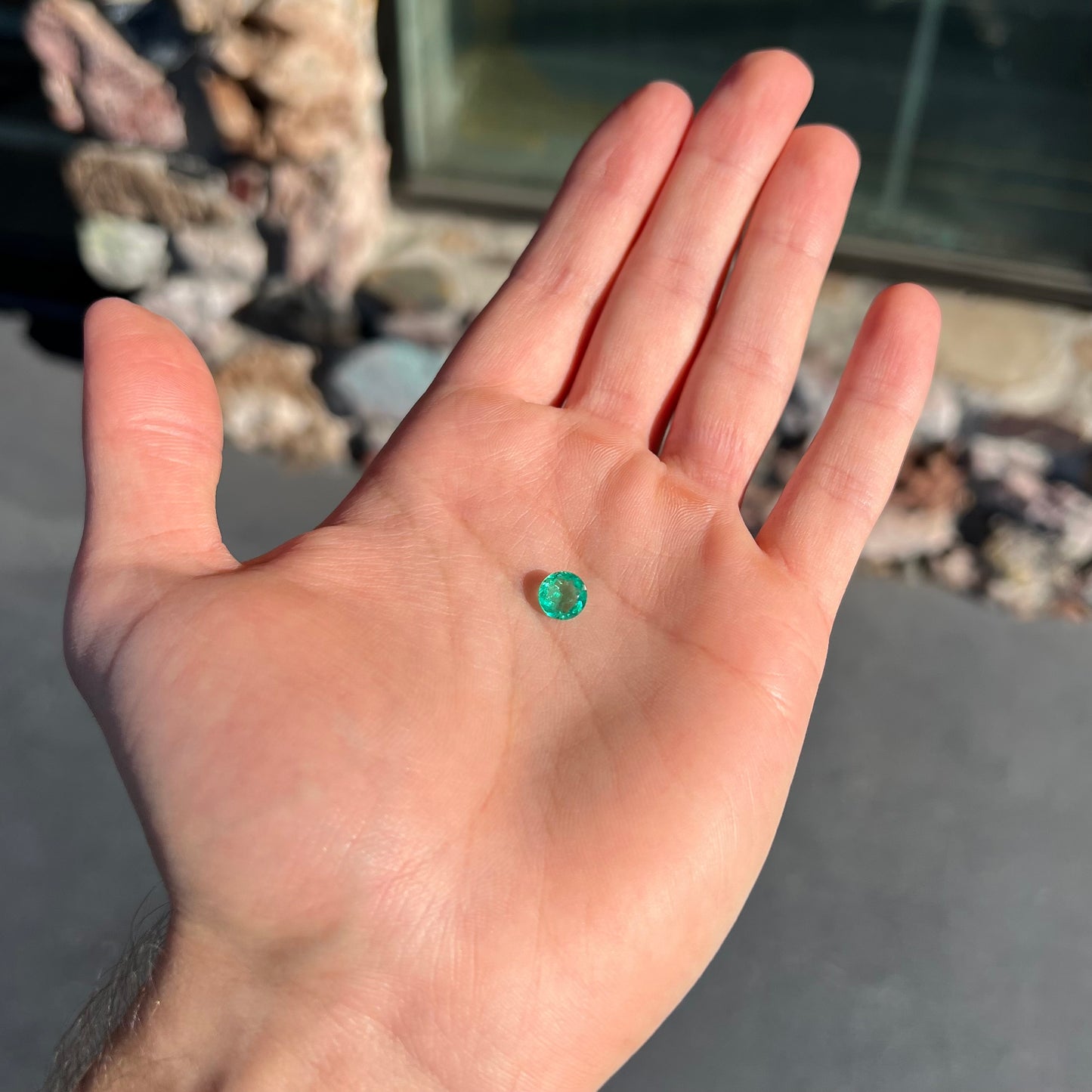 A loose, round brilliant cut natural emerald stone.
