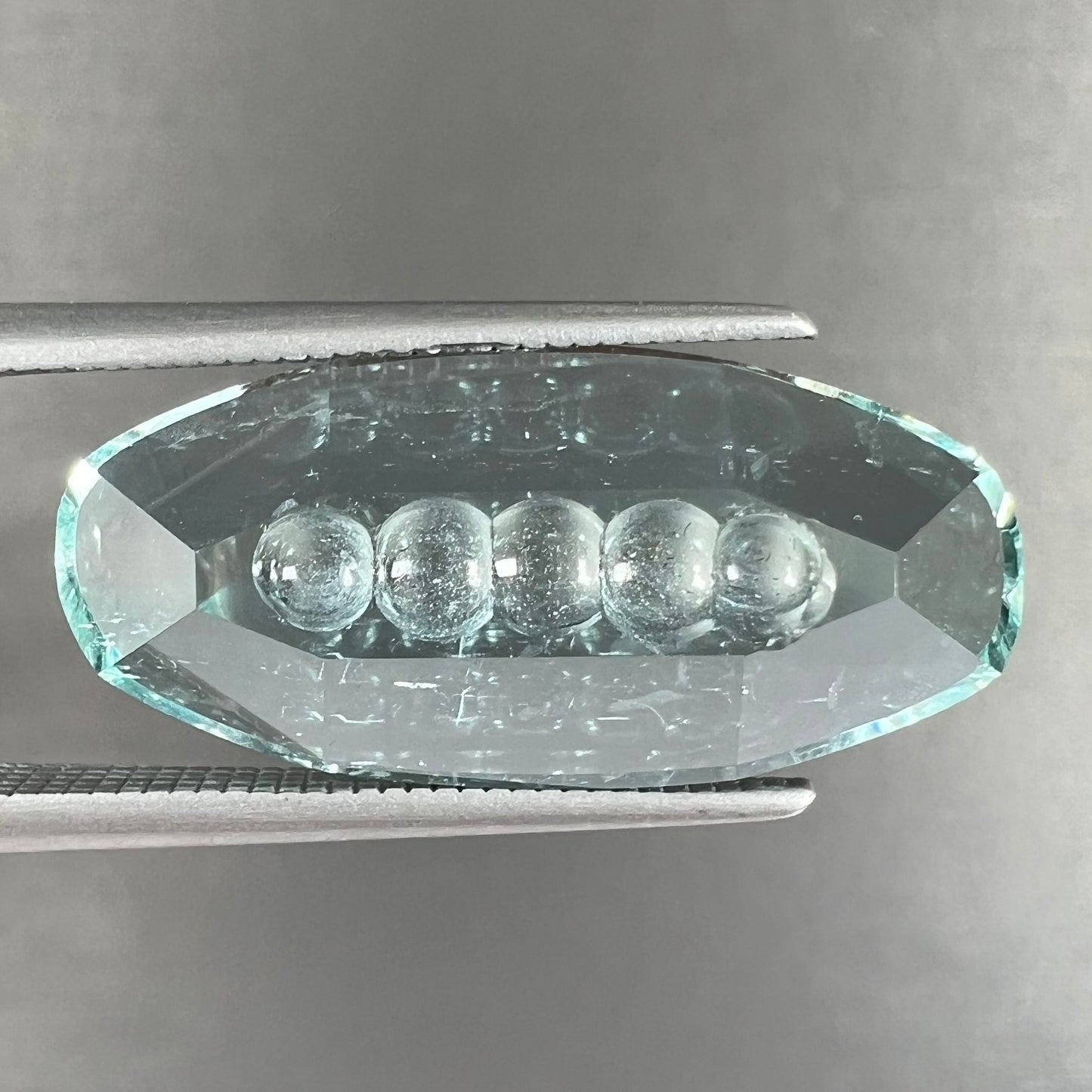An oval fantasy cut greenish blue aquamarine stone cut by gem carver, Arthur Lee Anderson.
