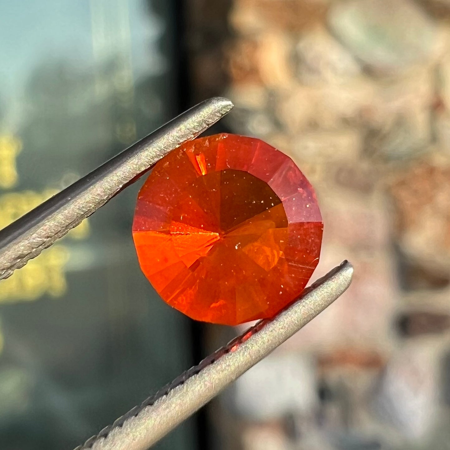 A faceted round cut natural Mexican fire opal stone. The stone is bright orange in color.