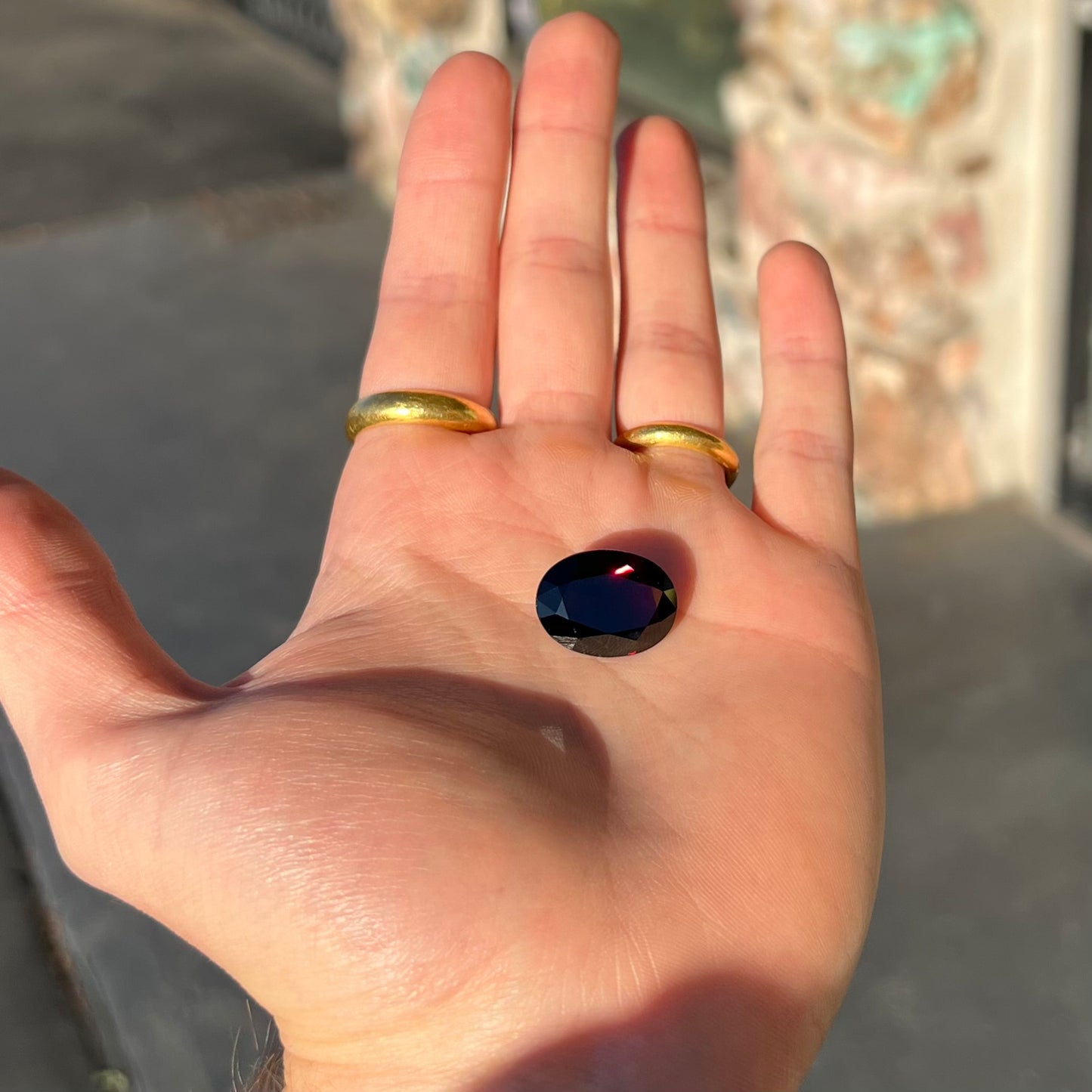A loose, faceted oval cut pyrope garnet gemstone. The stone is a deep, dark red color.