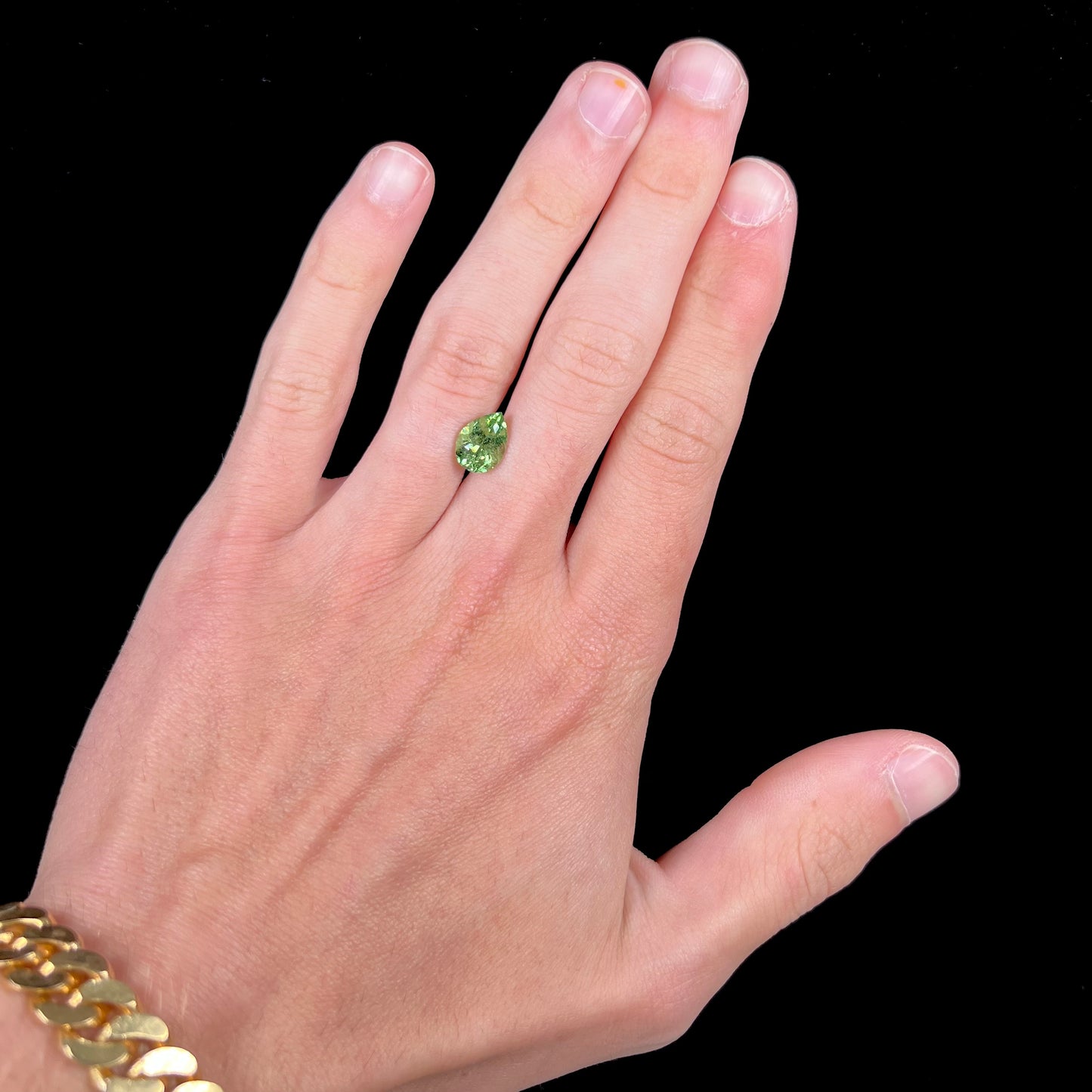 A loose, pear shaped tsavorite garnet gemstone. The stone is yellowish green.