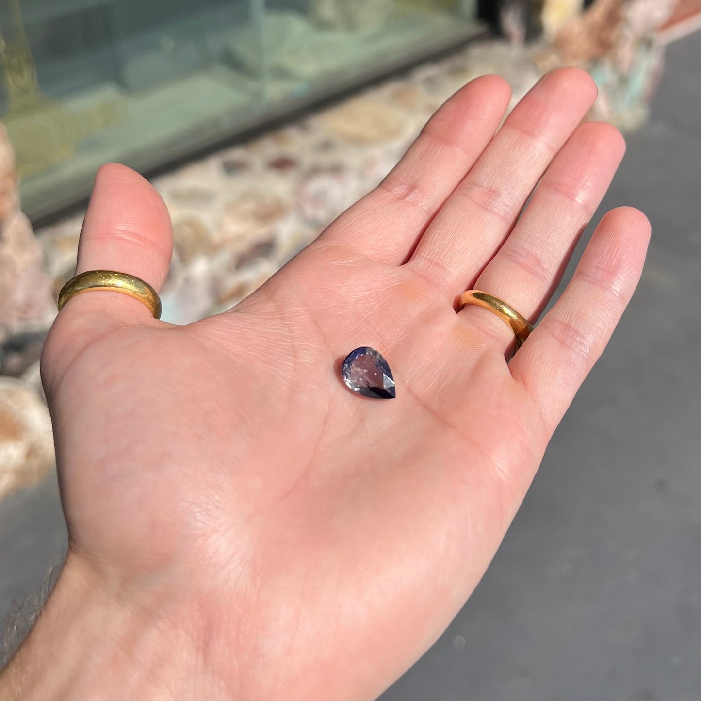 A loose, pear shaped bicolor iolite gemstone. The stone shows violite purple and silver colors.