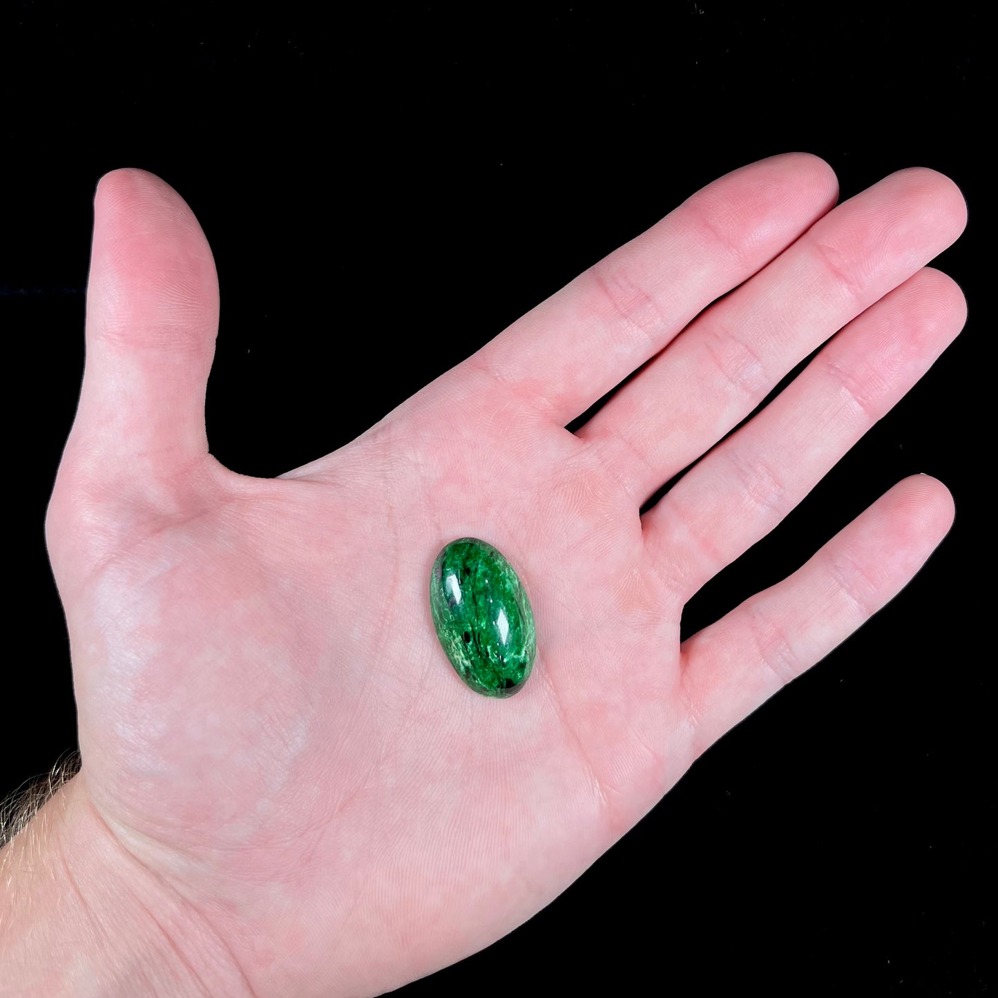 A loose, oval cabochon cut green maw sit sit stone.