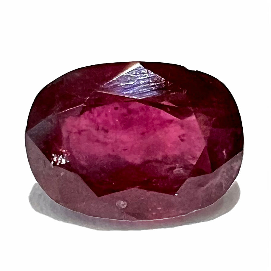 A loose, natural purplish ruby gemstone.  There is a small, minute chip on the girdle of the gem.