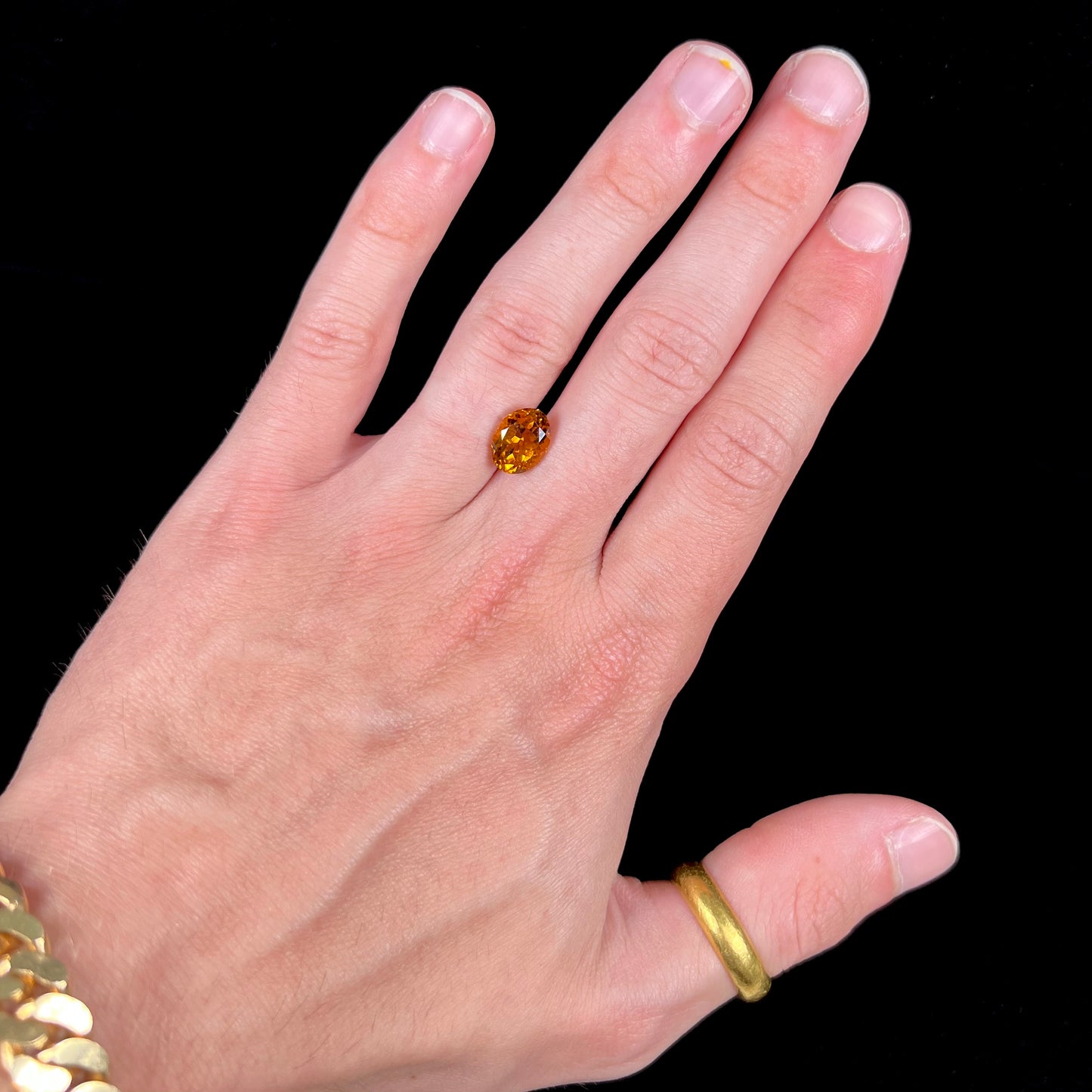 A loose, faceted oval cut orange dravite tourmaline gemstone.