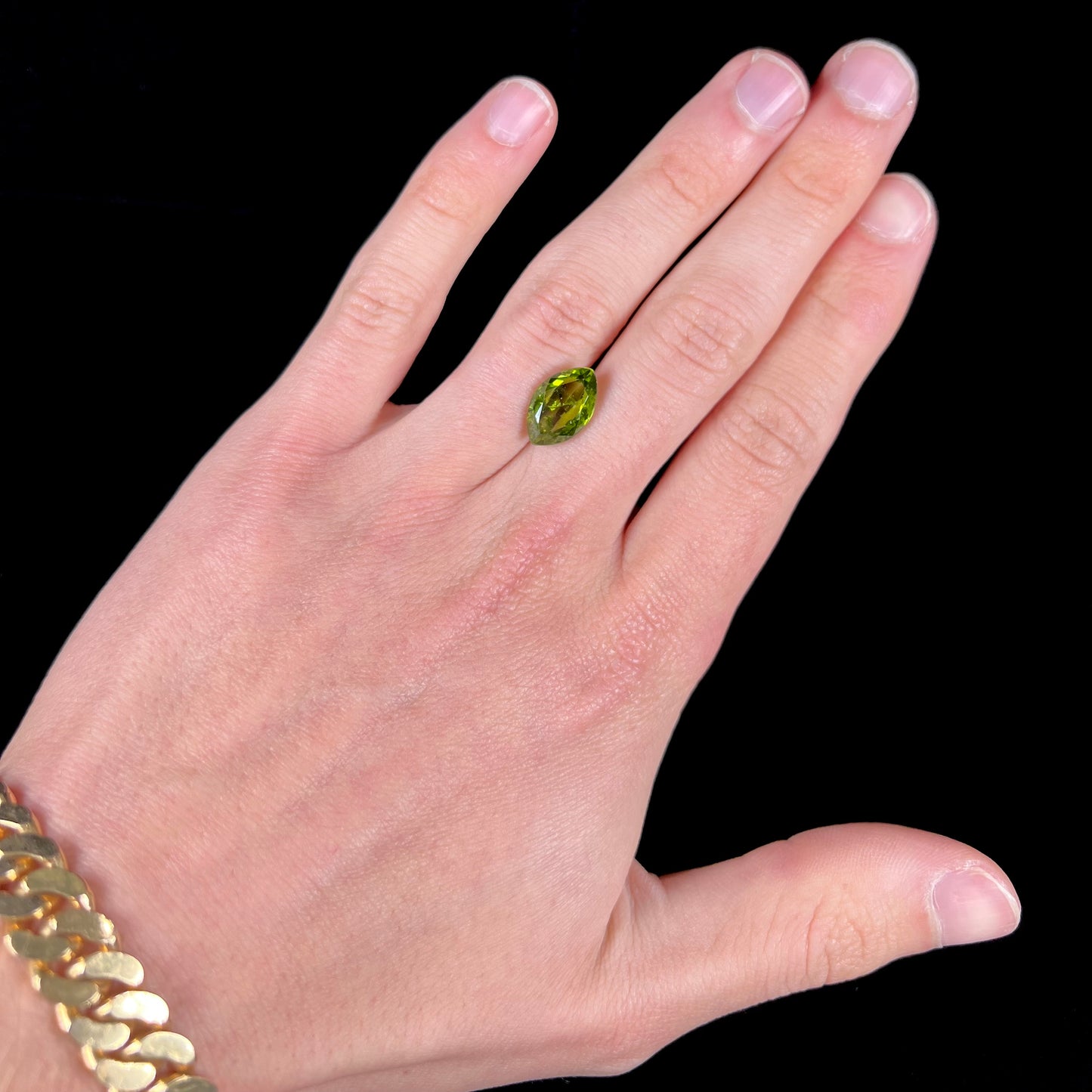 A loose, marquise cut peridot gemstone. The stone is an olive green color.