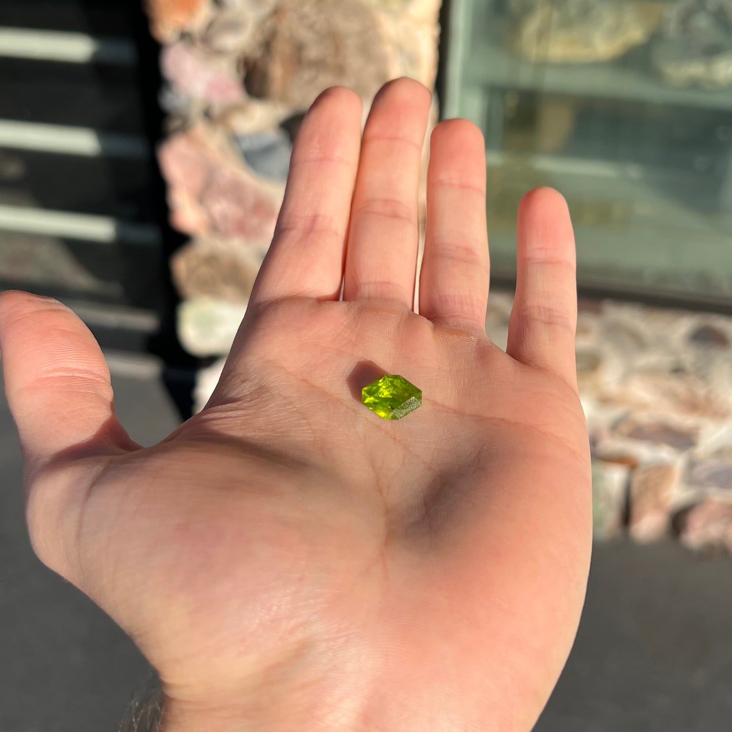 A loose, modified octagon peridot stone. The stone is a yellow green color.