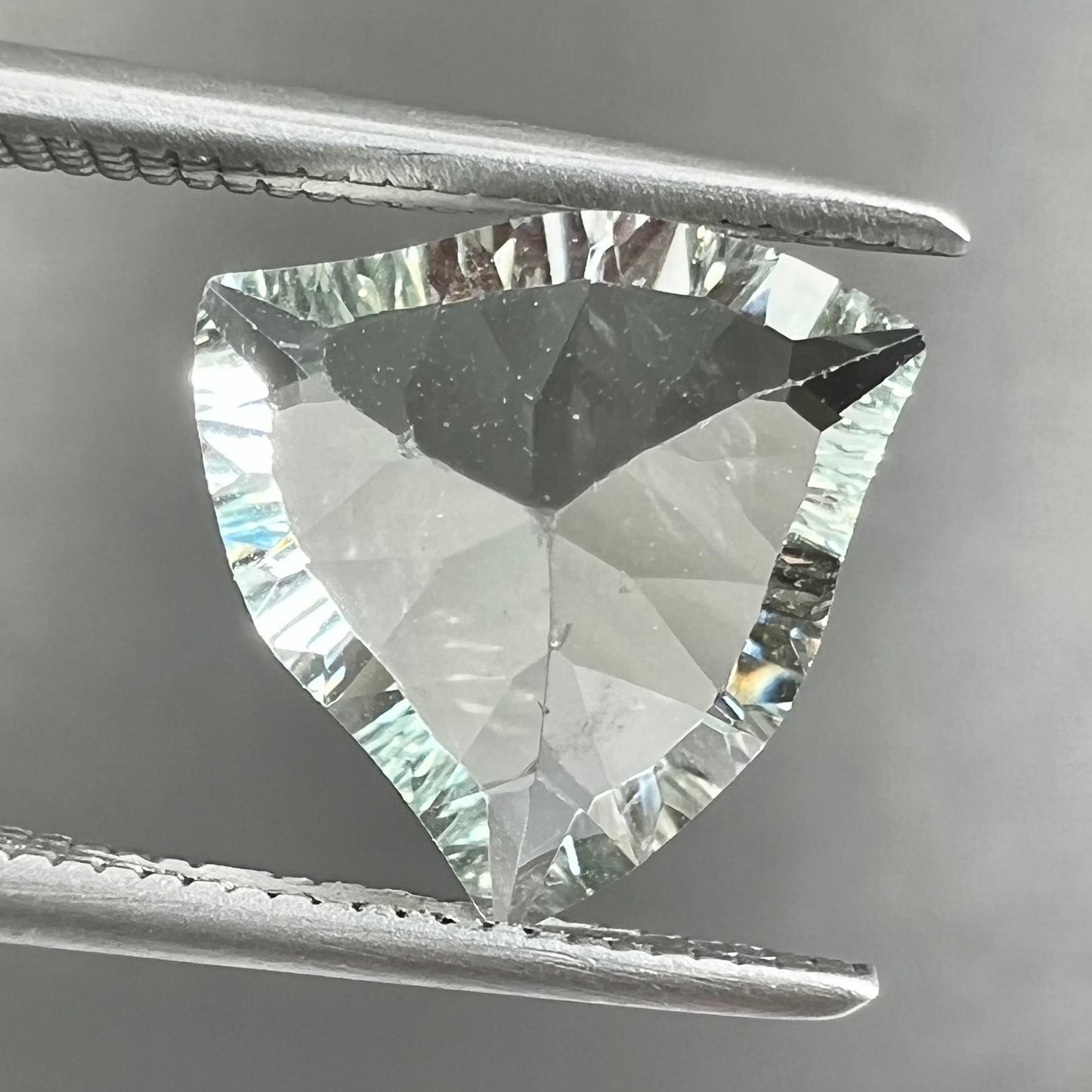 A loose, triangular fantasy cut prasiolite gemstone. Prasiolite is a light green variety of quartz.