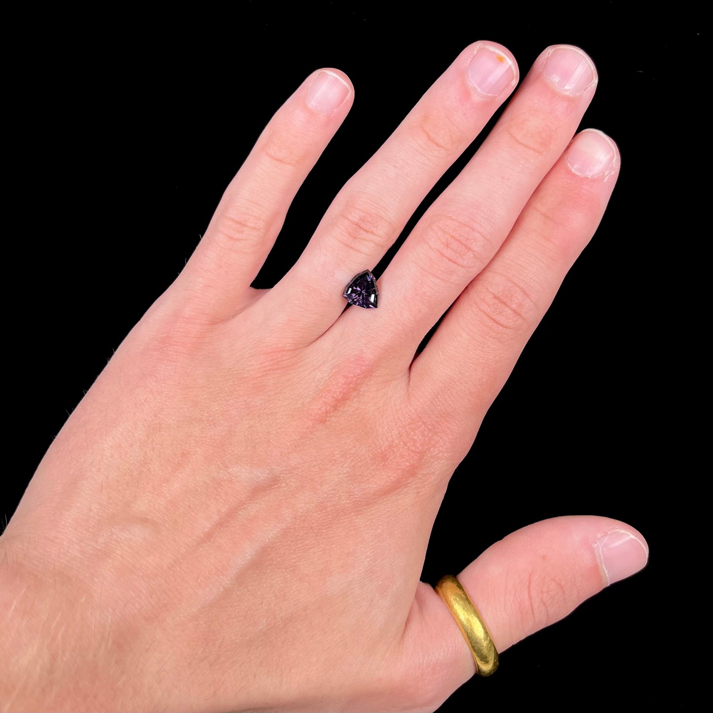 A loose, natural purple trillion cut spinel gemstone.