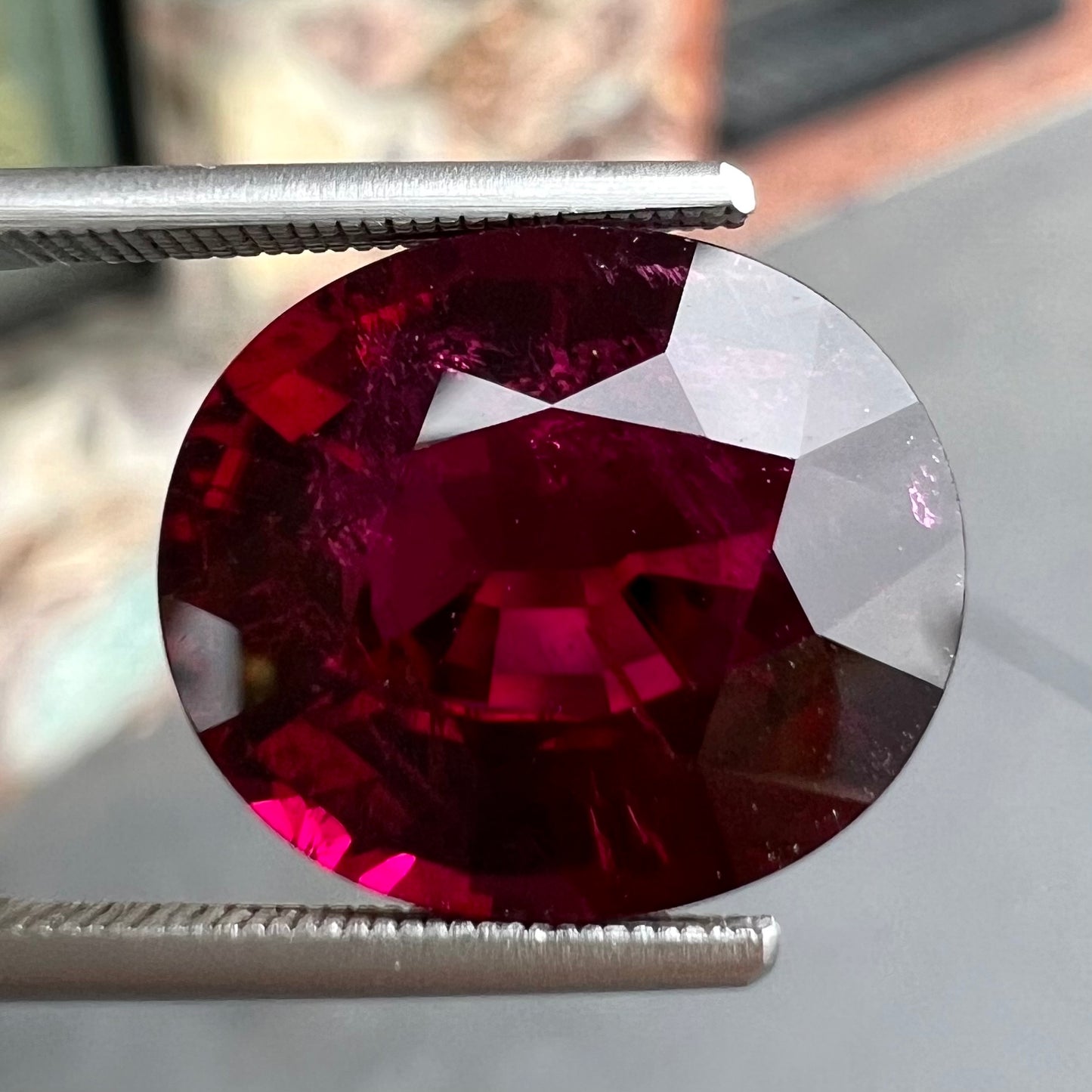 A loose, oval cut purplish red rubellite tourmaline stone.