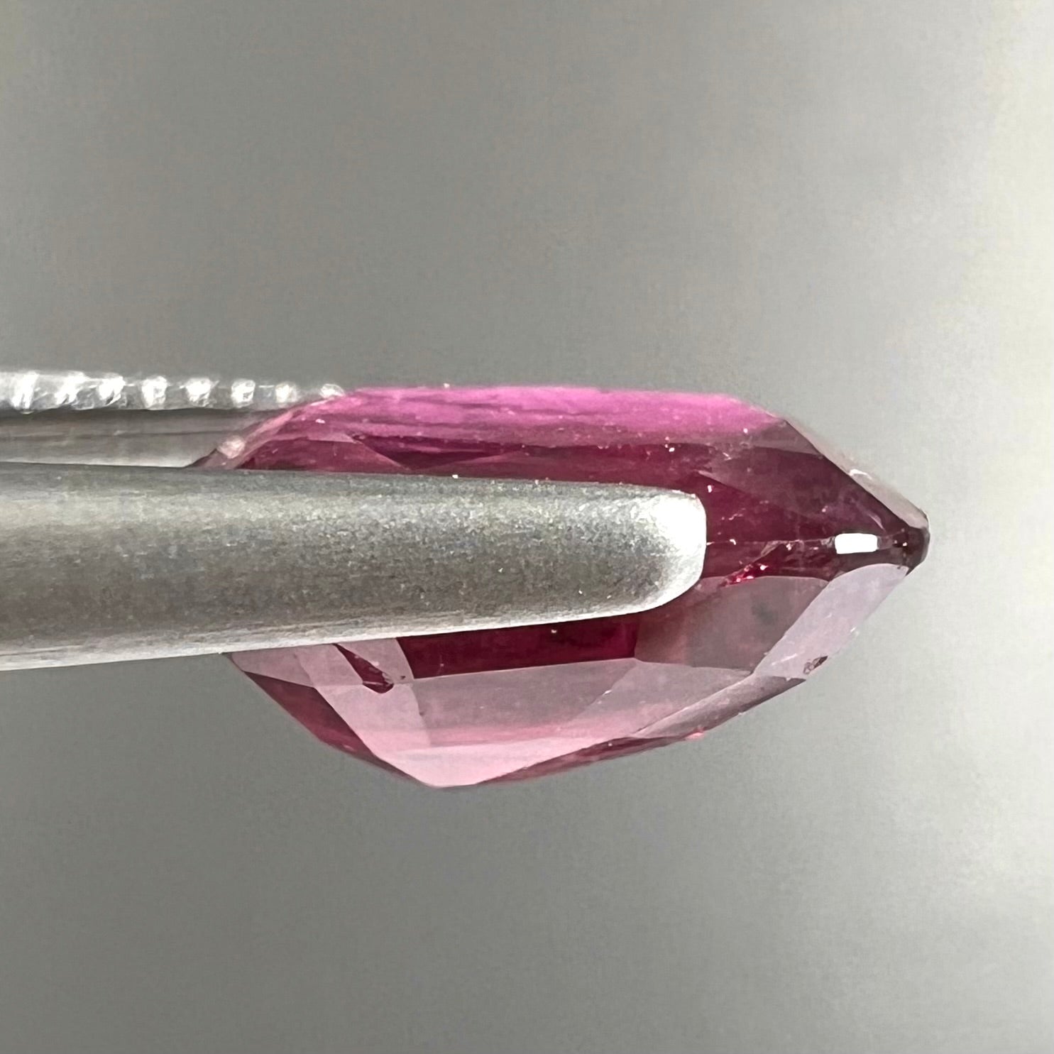 A loose, natural purplish ruby gemstone.  There is a small, minute chip on the girdle of the gem.