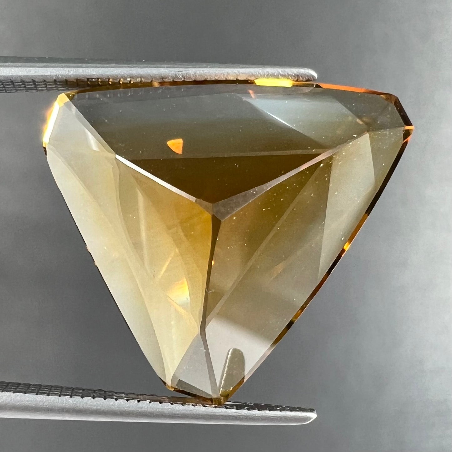 A loose, triangular fantasy cut yellow citrine stone cut by Arthur Lee Anderson.