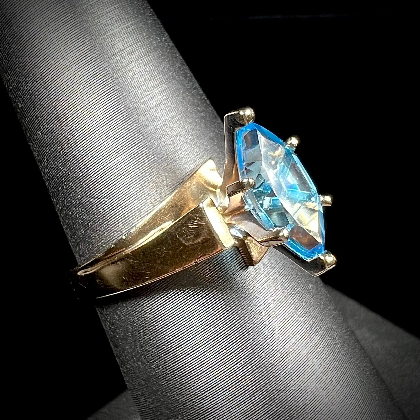A ladies' estate yellow gold ring, prong set with a marquise cut blue topaz stone. There are scratches on the shank.