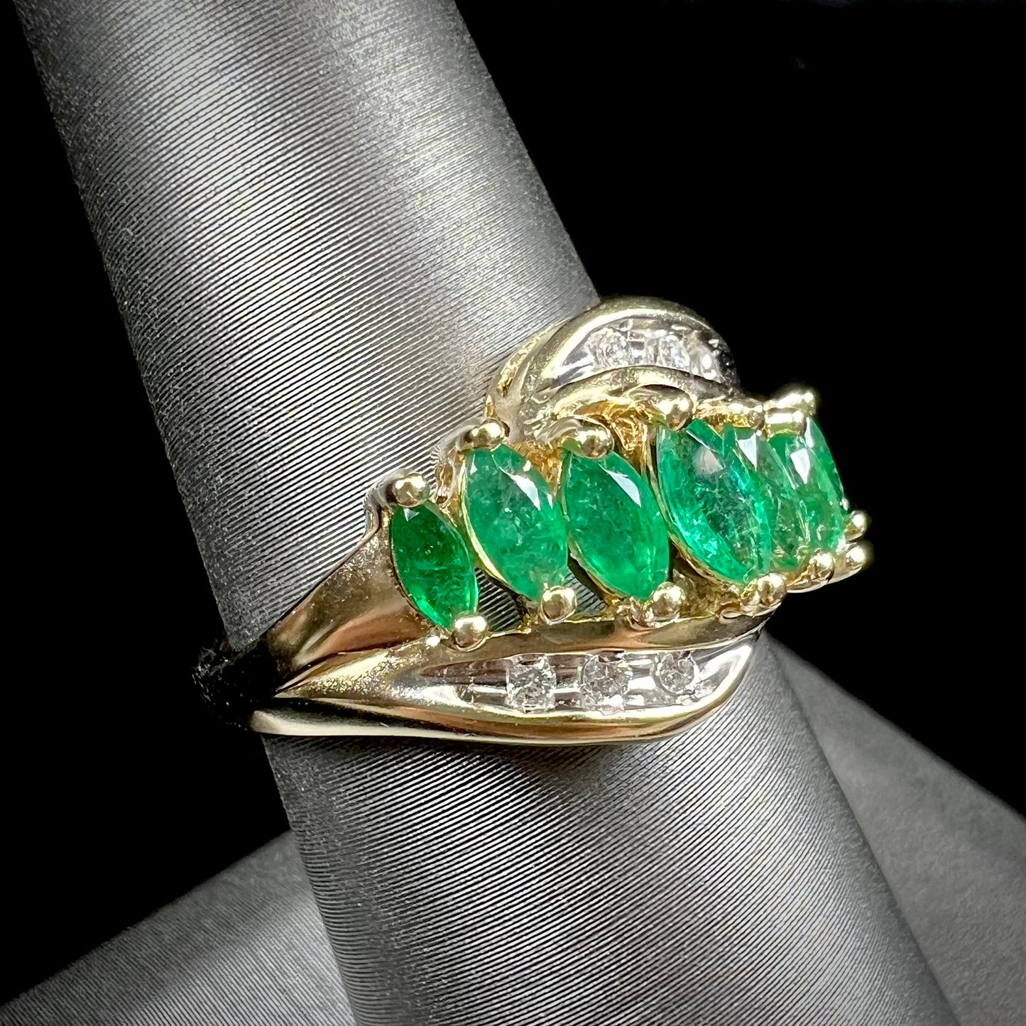 A vintage, 1970's style yellow gold ring set with marquise cut emeralds and round brilliant cut diamonds.