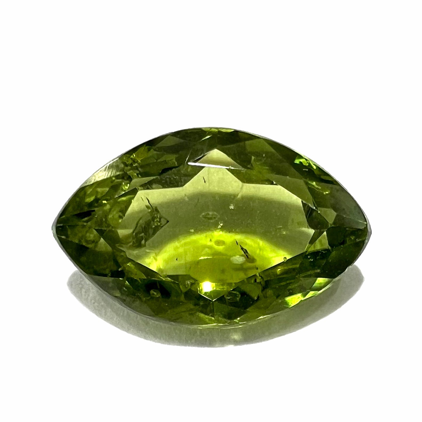 A loose, marquise cut peridot gemstone. The stone is an olive green color.