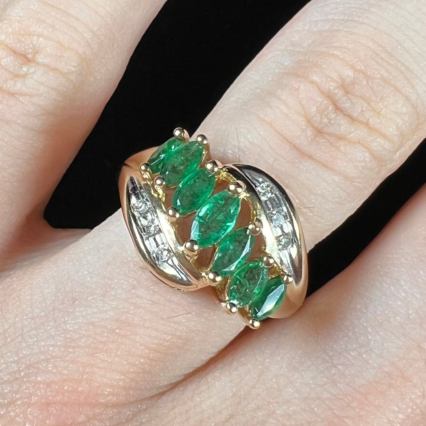 A vintage, 1970's style yellow gold ring set with marquise cut emeralds and round brilliant cut diamonds.