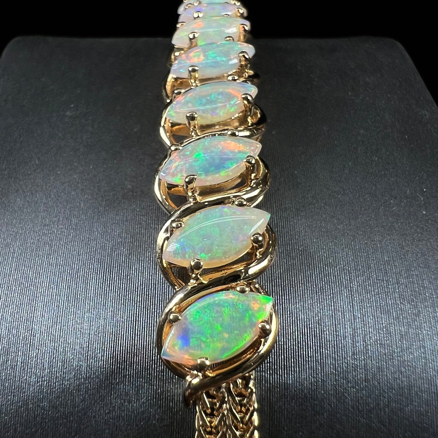 A ladies' yellow gold bracelet prong set with eight natural, marquise cabochon cut opals.