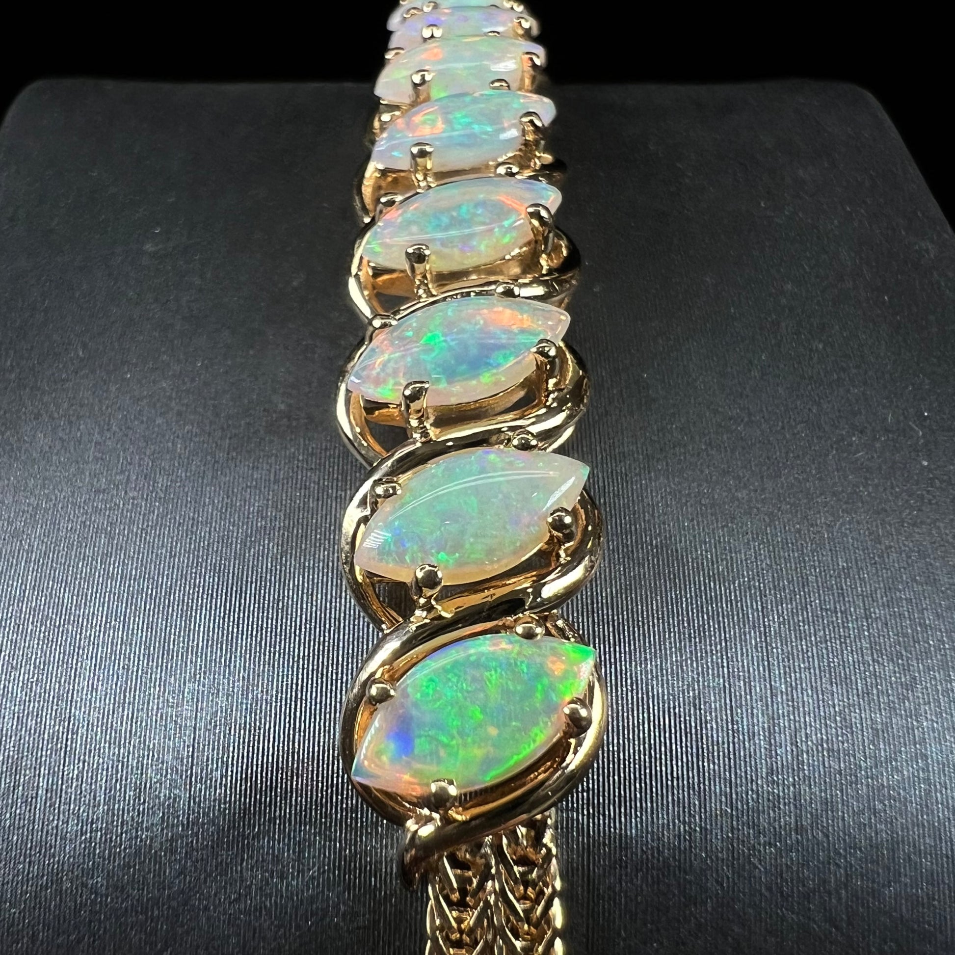 A ladies' yellow gold bracelet prong set with eight natural, marquise cabochon cut opals.
