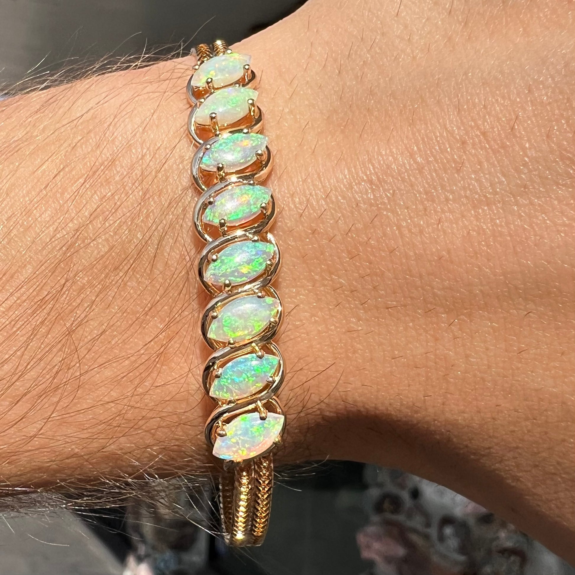 A ladies' yellow gold bracelet prong set with eight natural, marquise cabochon cut opals.