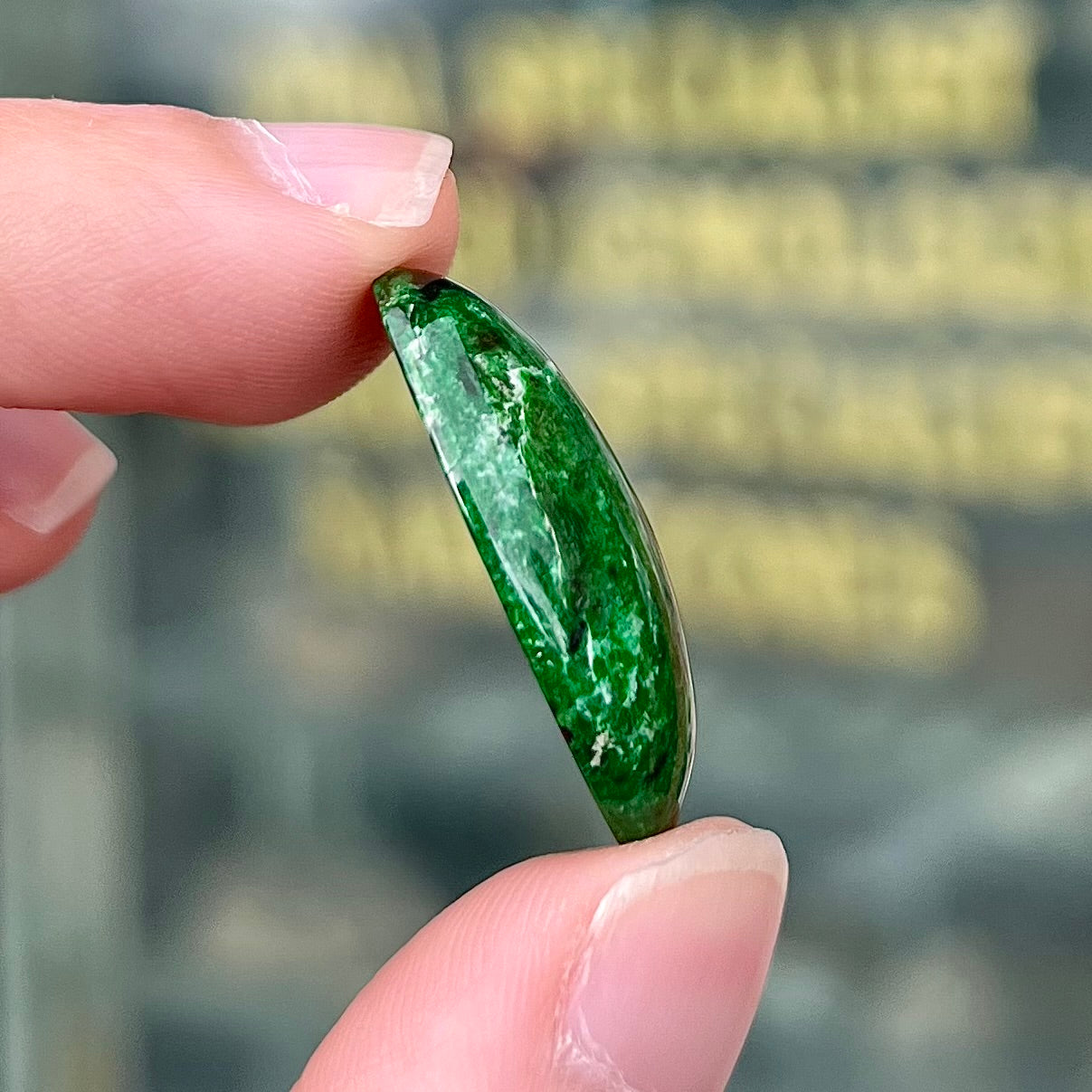 A loose, oval cabochon cut green maw sit sit stone.