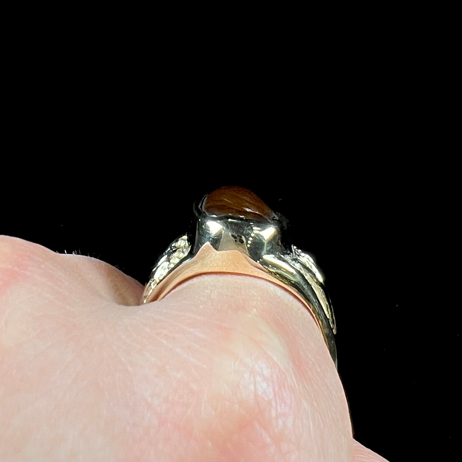 A man's yellow gold solitaire ring set with a freeform shaped Mexican fire agate stone.  The stone has a purple bull's eye pattern.