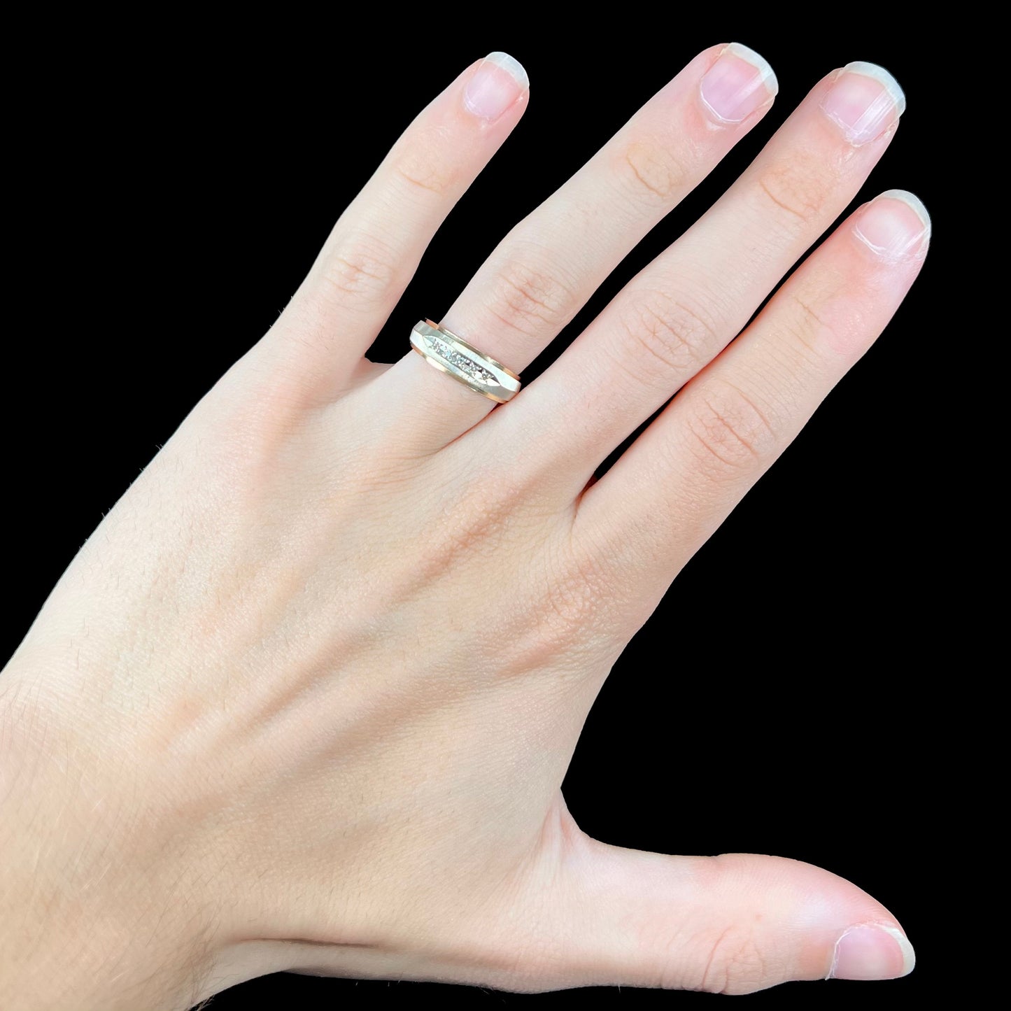 A unisex, two-tone white and yellow gold diamond wedding band. The white gold is textured.