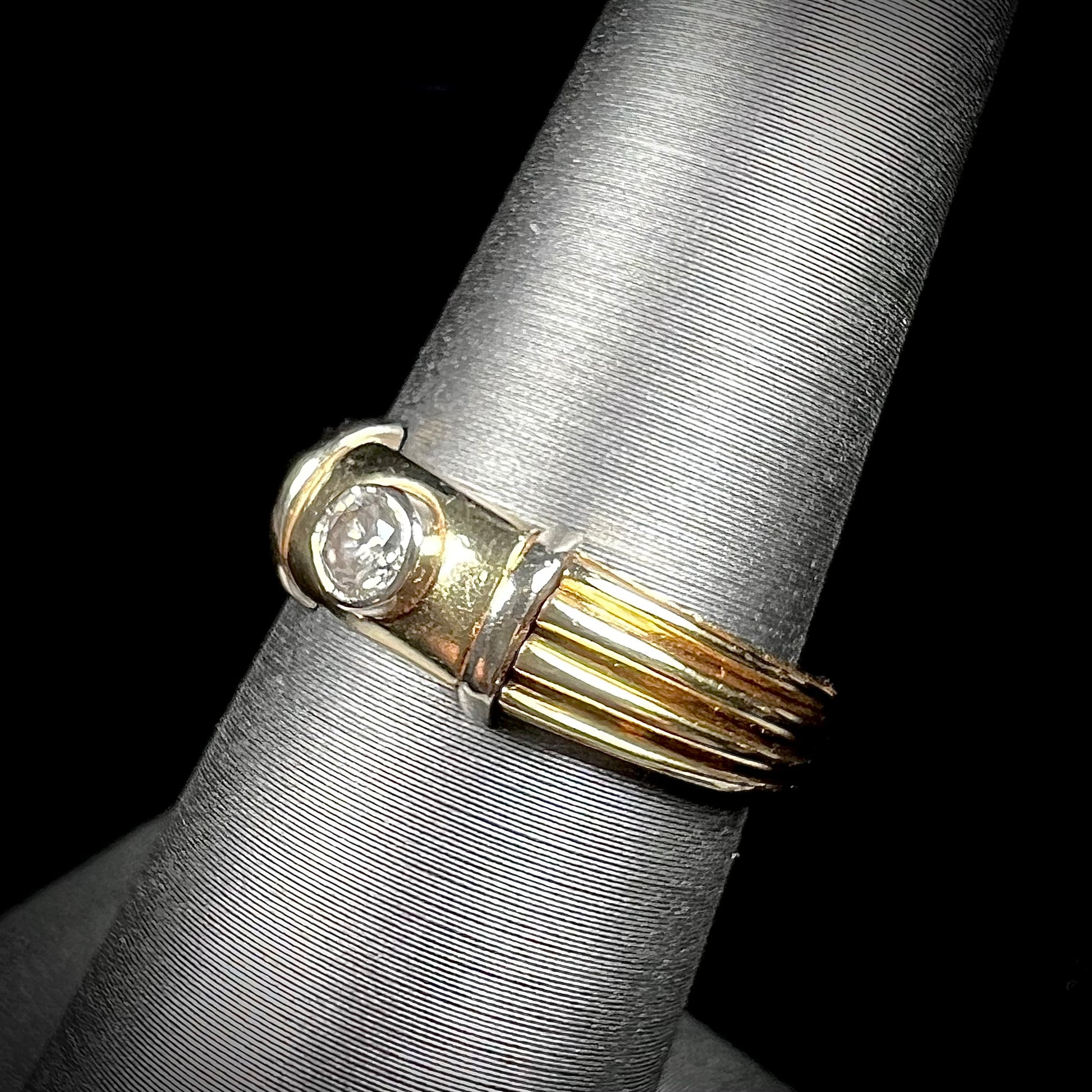 A unisex, vintage style two tone yellow and white gold wedding ring bezel set with a round diamond.