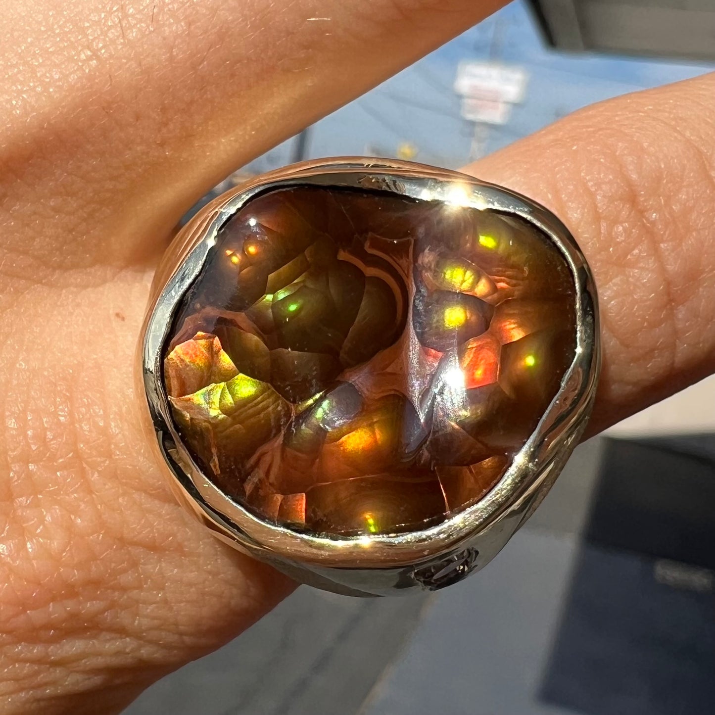 A men's heavy yellow gold ring set with a Mexican fire agate stone and three round brilliant cut diamond accents.