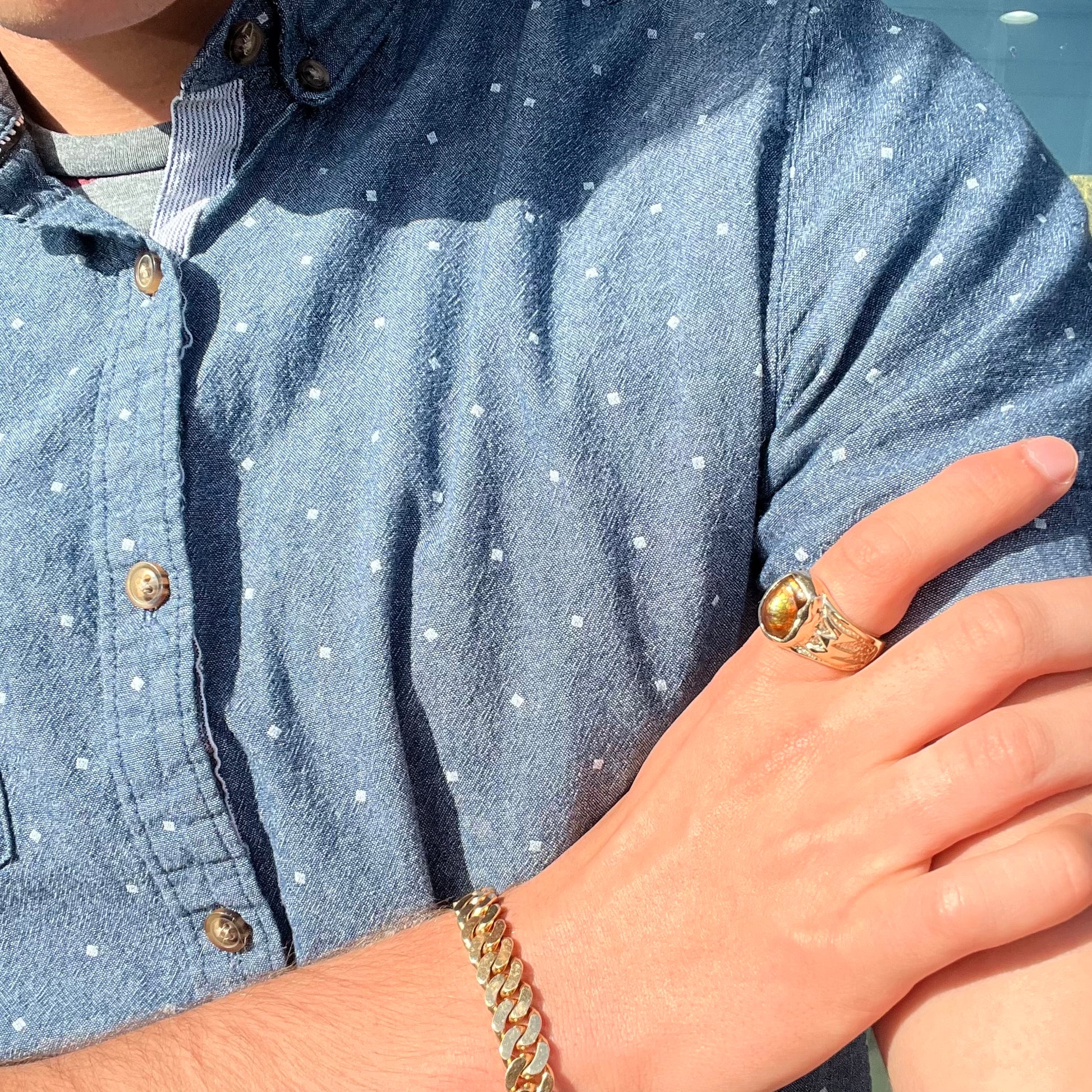A man's yellow gold solitaire ring set with a freeform shaped Mexican fire agate stone.  The stone has a purple bull's eye pattern.