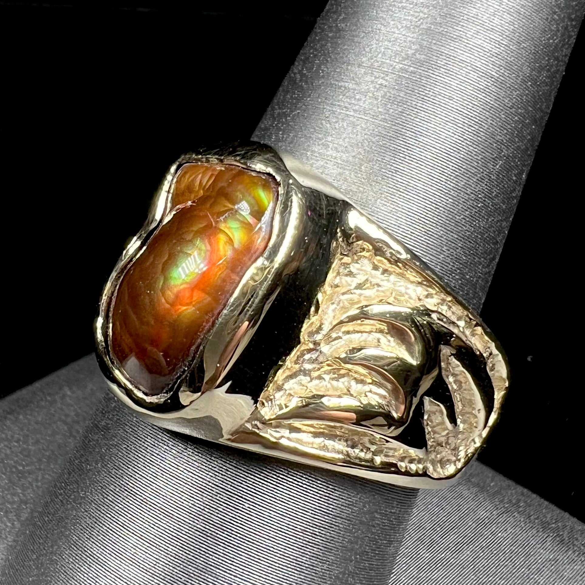 A man's yellow gold solitaire ring set with a freeform shaped Mexican fire agate stone.  The stone has a purple bull's eye pattern.