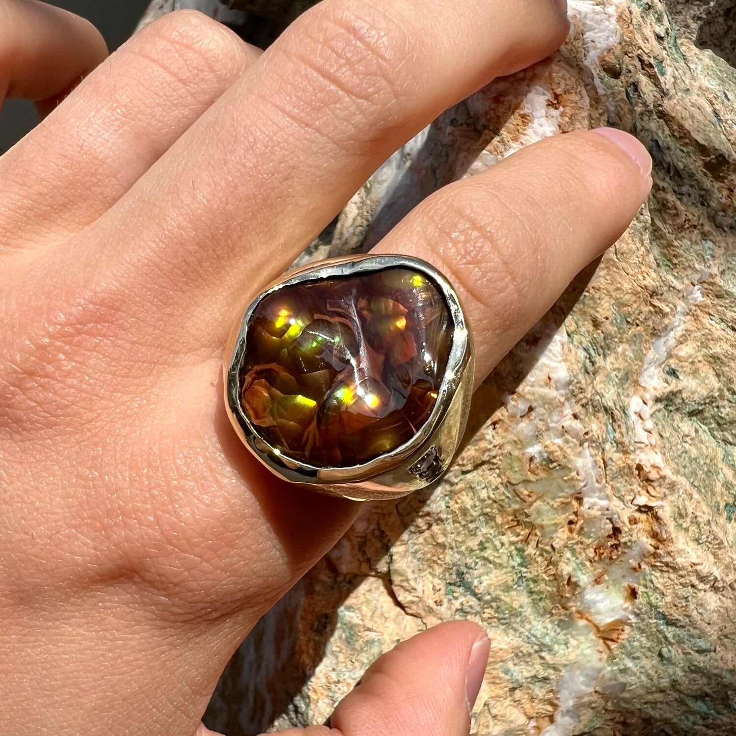 A men's heavy yellow gold ring set with a Mexican fire agate stone and three round brilliant cut diamond accents.