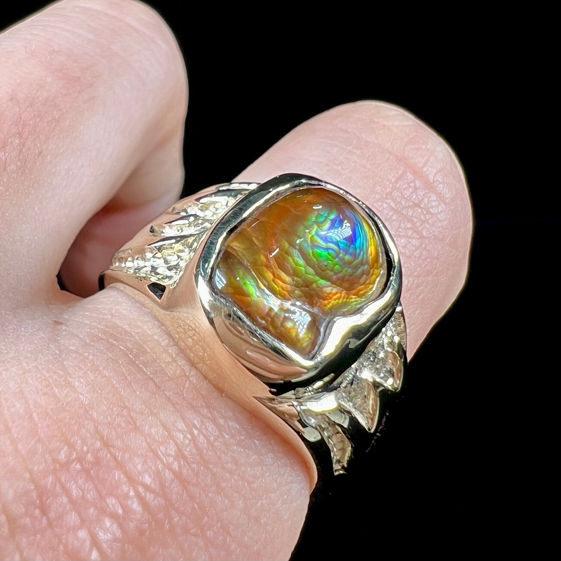 A man's yellow gold solitaire ring set with a freeform shaped Mexican fire agate stone.  The stone has a purple bull's eye pattern.