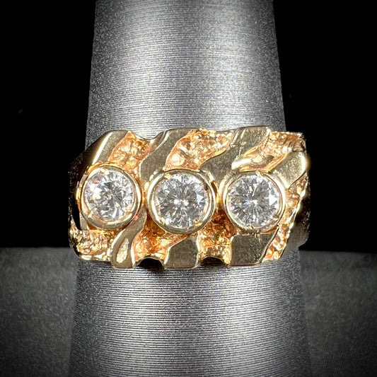 A men's yellow gold ring set with three round brilliant cut diamonds.  There are scratches along the shank.