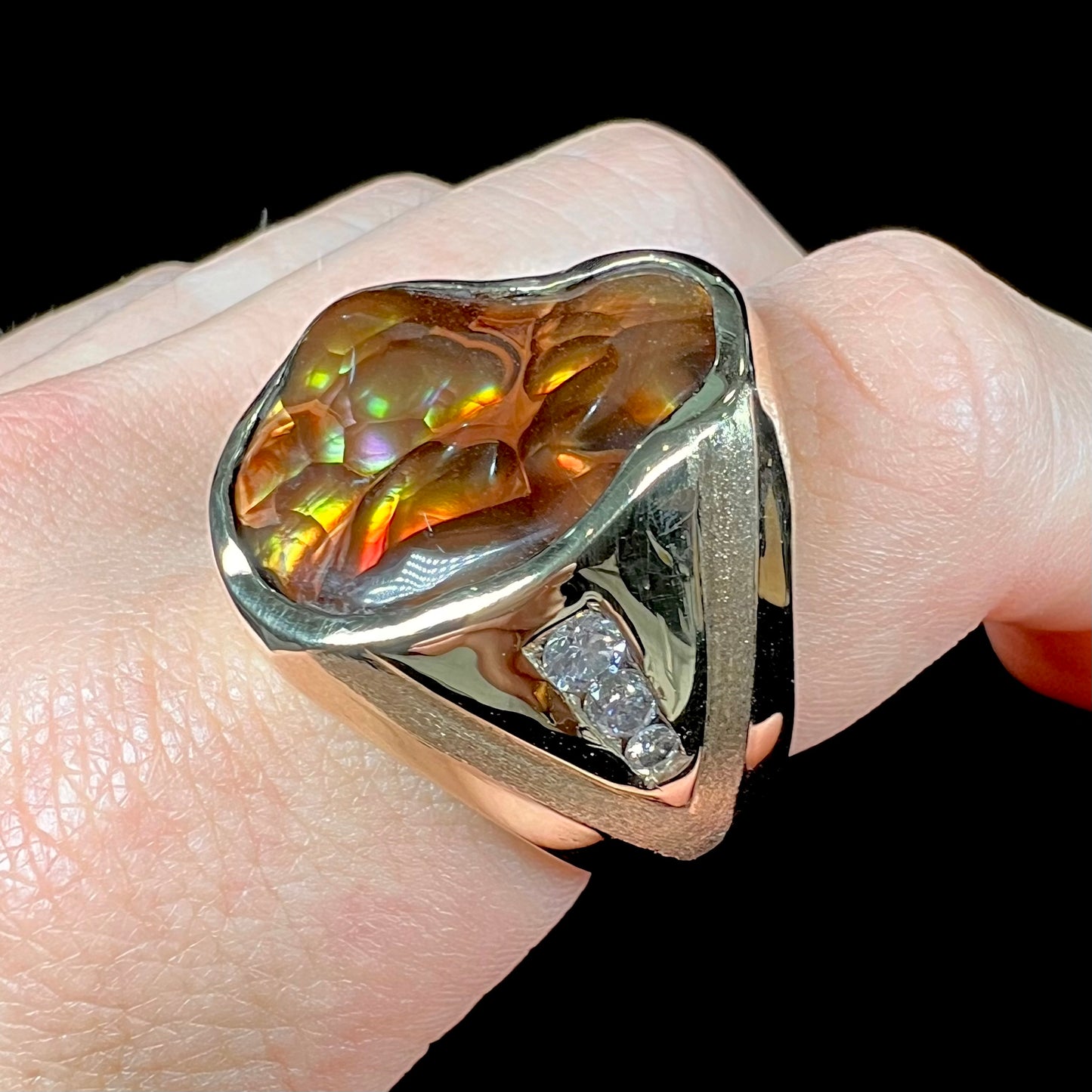 A men's heavy yellow gold ring set with a Mexican fire agate stone and three round brilliant cut diamond accents.