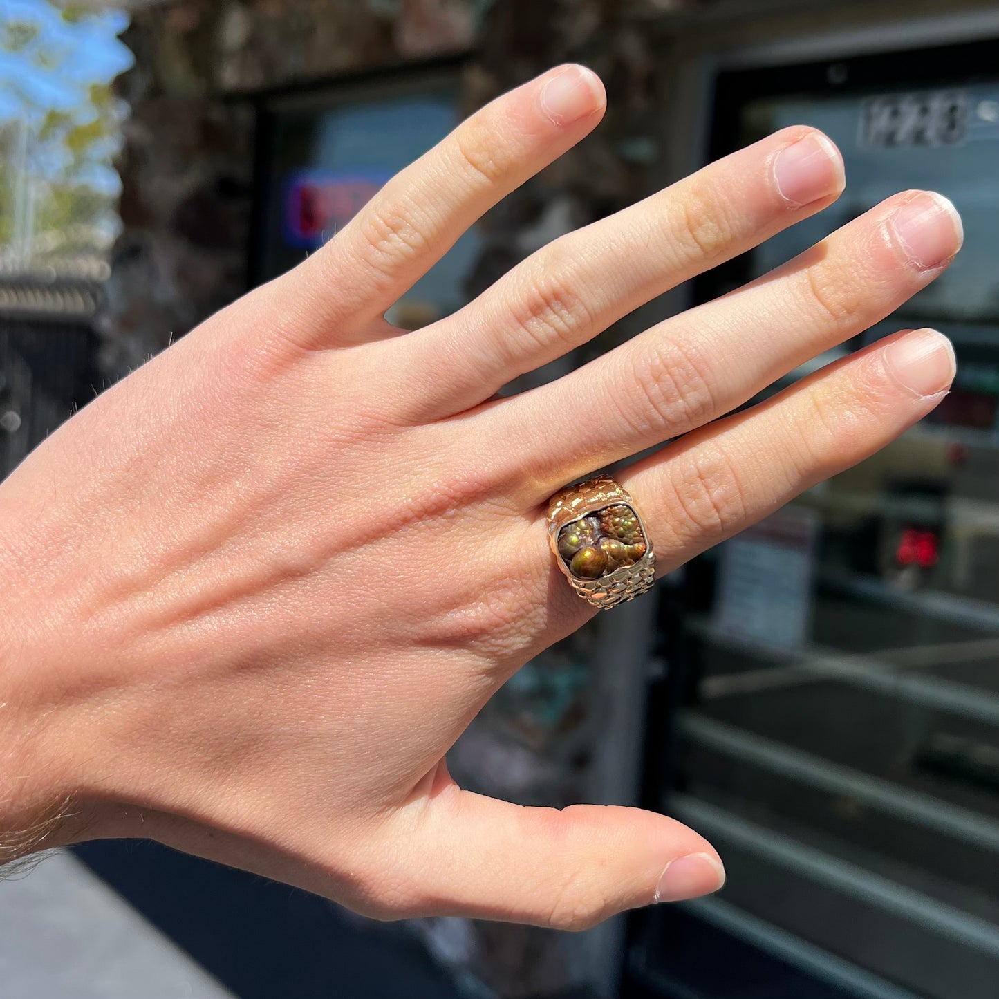 A men's yellow gold, nugget style ring set with a bubbly, California fire agate stone.