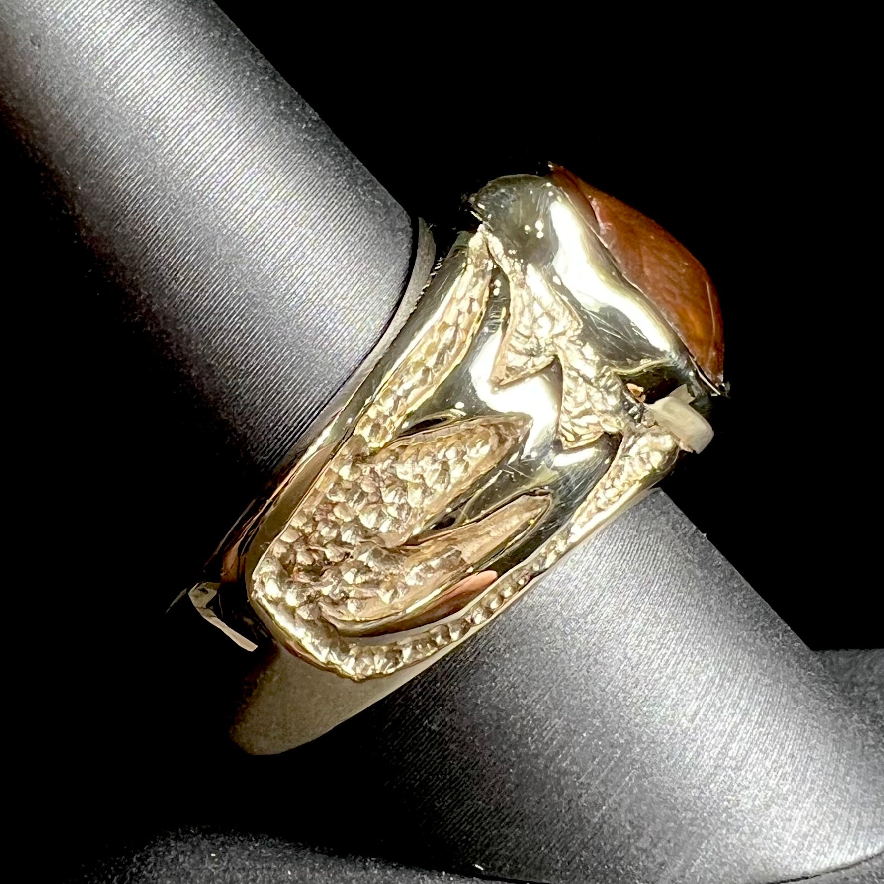 A man's yellow gold solitaire ring set with a freeform shaped Mexican fire agate stone.  The stone has a purple bull's eye pattern.