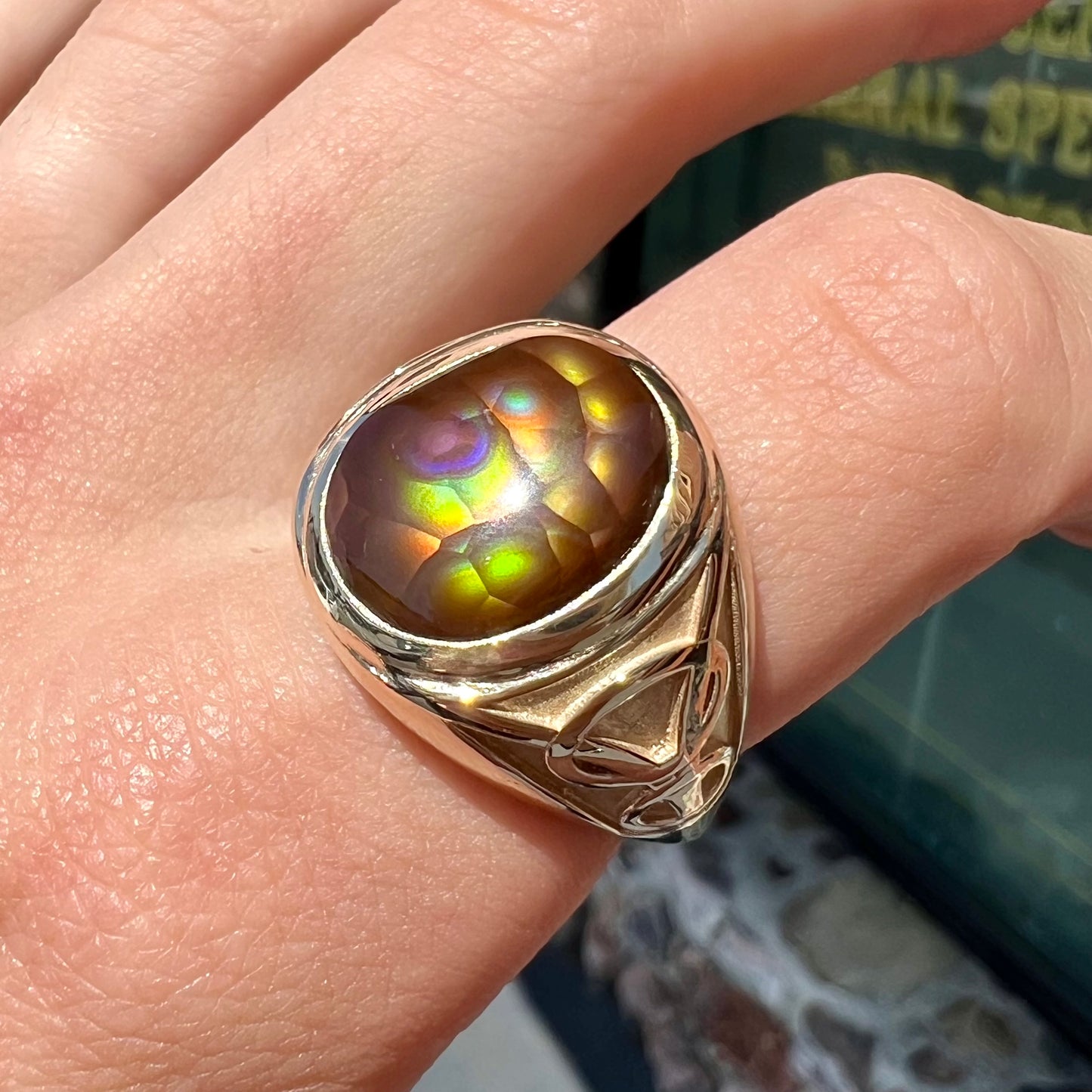 A men's solid yellow gold ring set with a Mexican fire agate stone.  The fire agate has a puple bull's eye pattern.