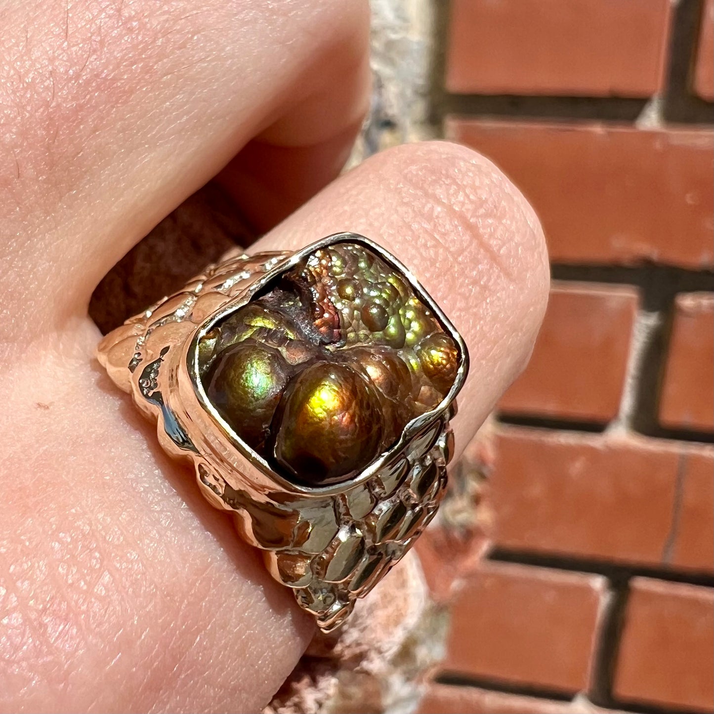 A men's yellow gold, nugget style ring set with a bubbly, California fire agate stone.